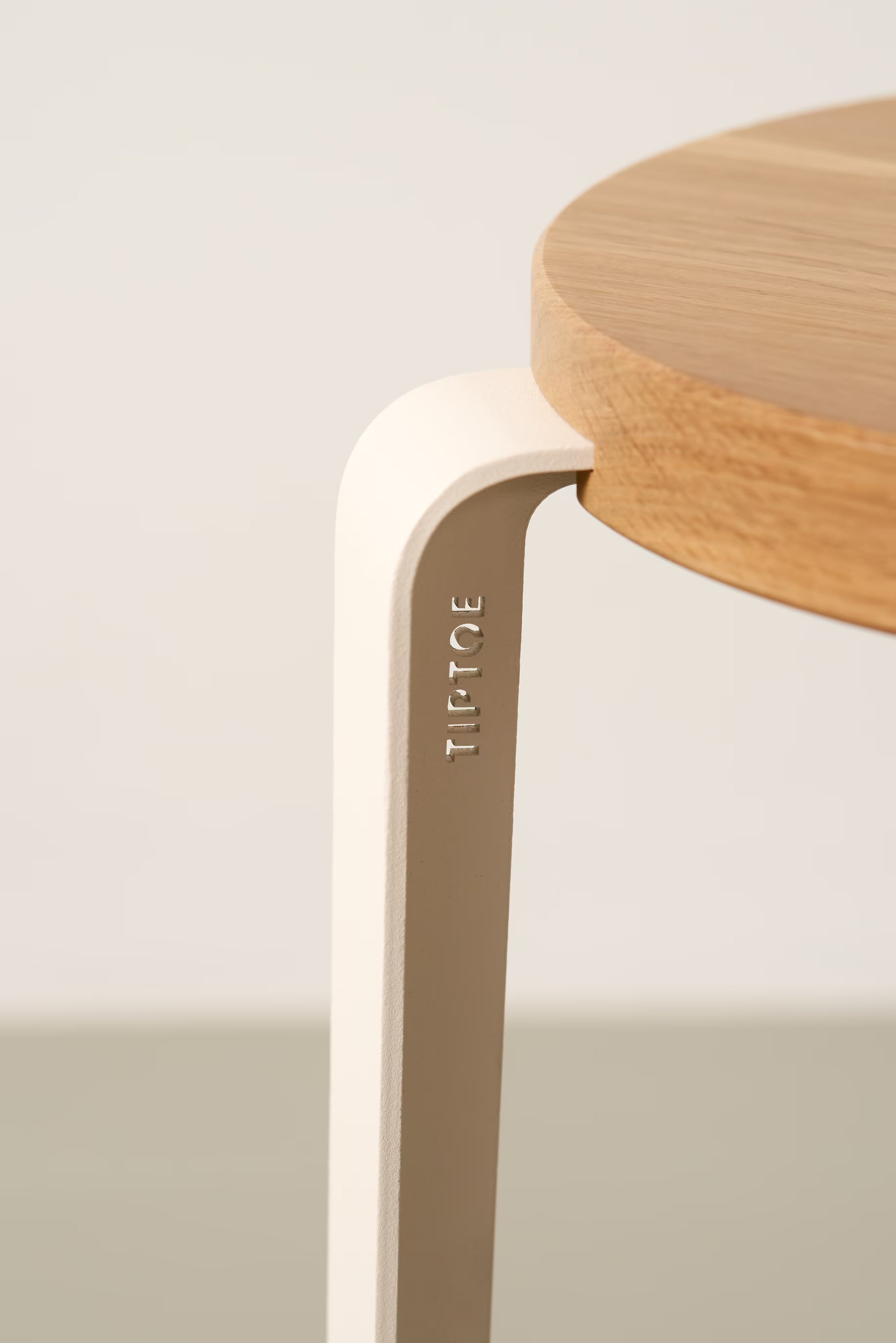Détail du tabouret Lou Tiptoe avec assise en chêne massif et piétement en acier blanc crème, présenté sur fond neutre.