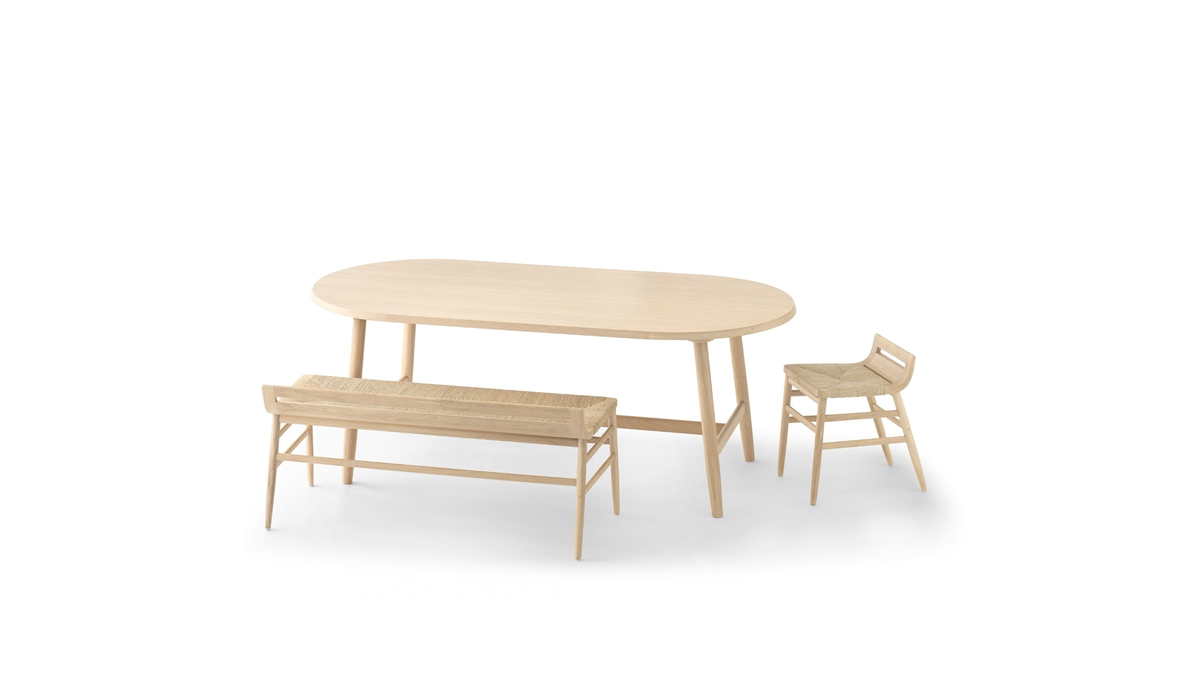 Banc Kimua en bois et paille par Alki, accompagné d’une table ovale assortie et d’un tabouret sur fond blanc