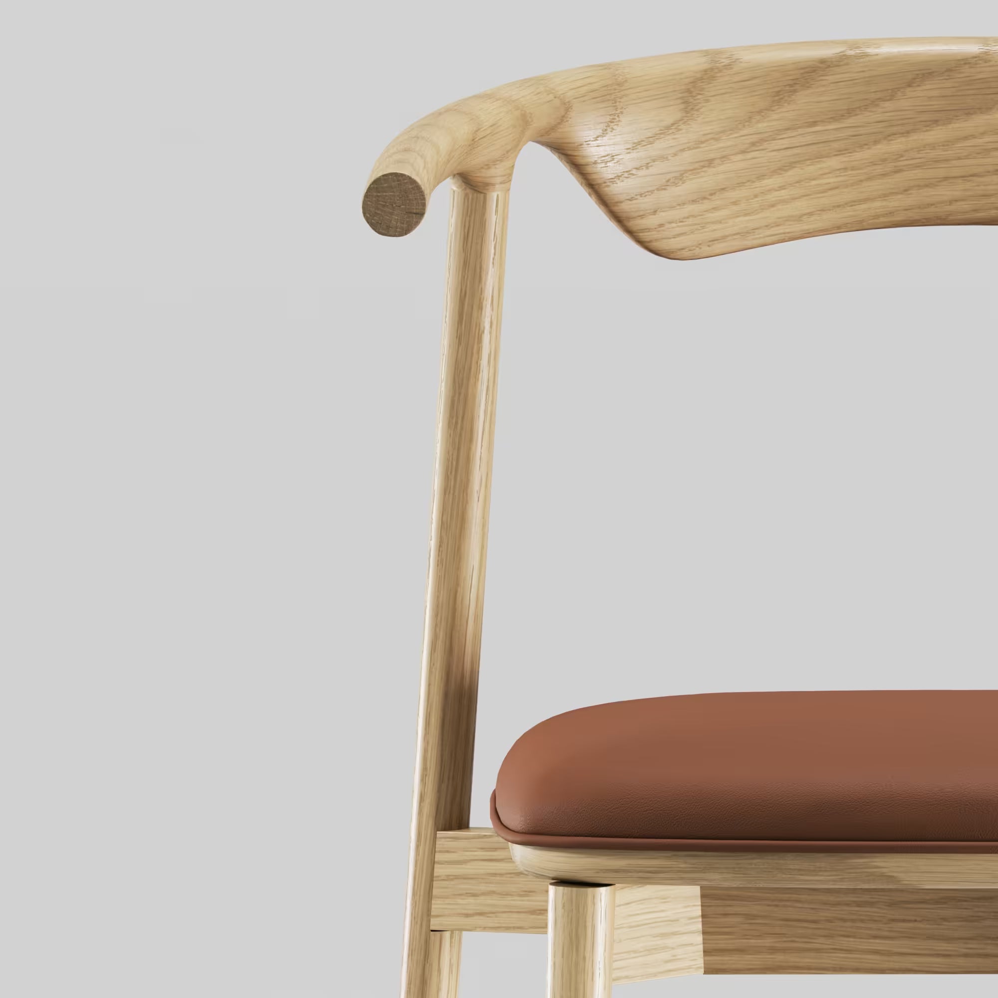 Zoom sur la chaise Pala de WeWood, en chêne massif et cuir cognac, accoudoir sculpté et assise arrondie vue rapprochée sur fond gris clair