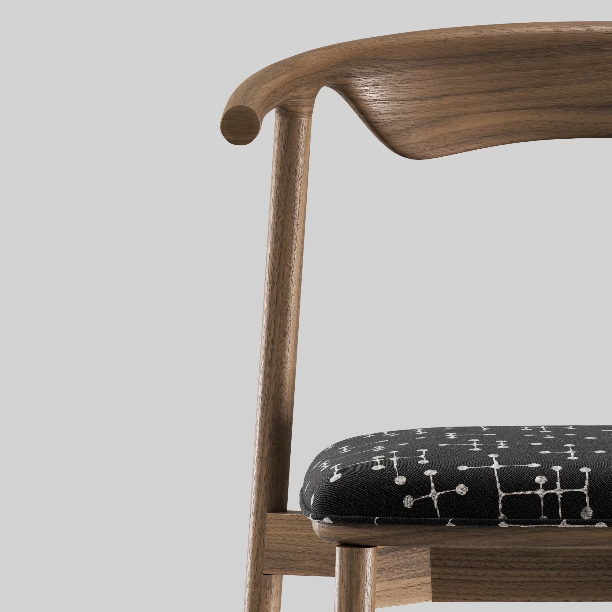 Zoom sur la chaise Pala de WeWood, en noyer massif et tissu, accoudoir sculpté et assise arrondie vue rapprochée sur fond gris clair