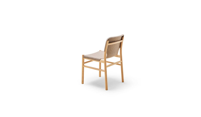 Chaise Alki en bois naturel avec assise et dossier en tissu marron clair, vue arrière trois-quarts sur fond blanc.