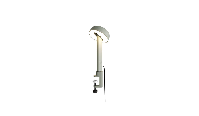 Lampe à pince gris eucalyptus, Nod de Tiptoe, vue latérale avec l’ampoule allumée, abat-jour circulaire.