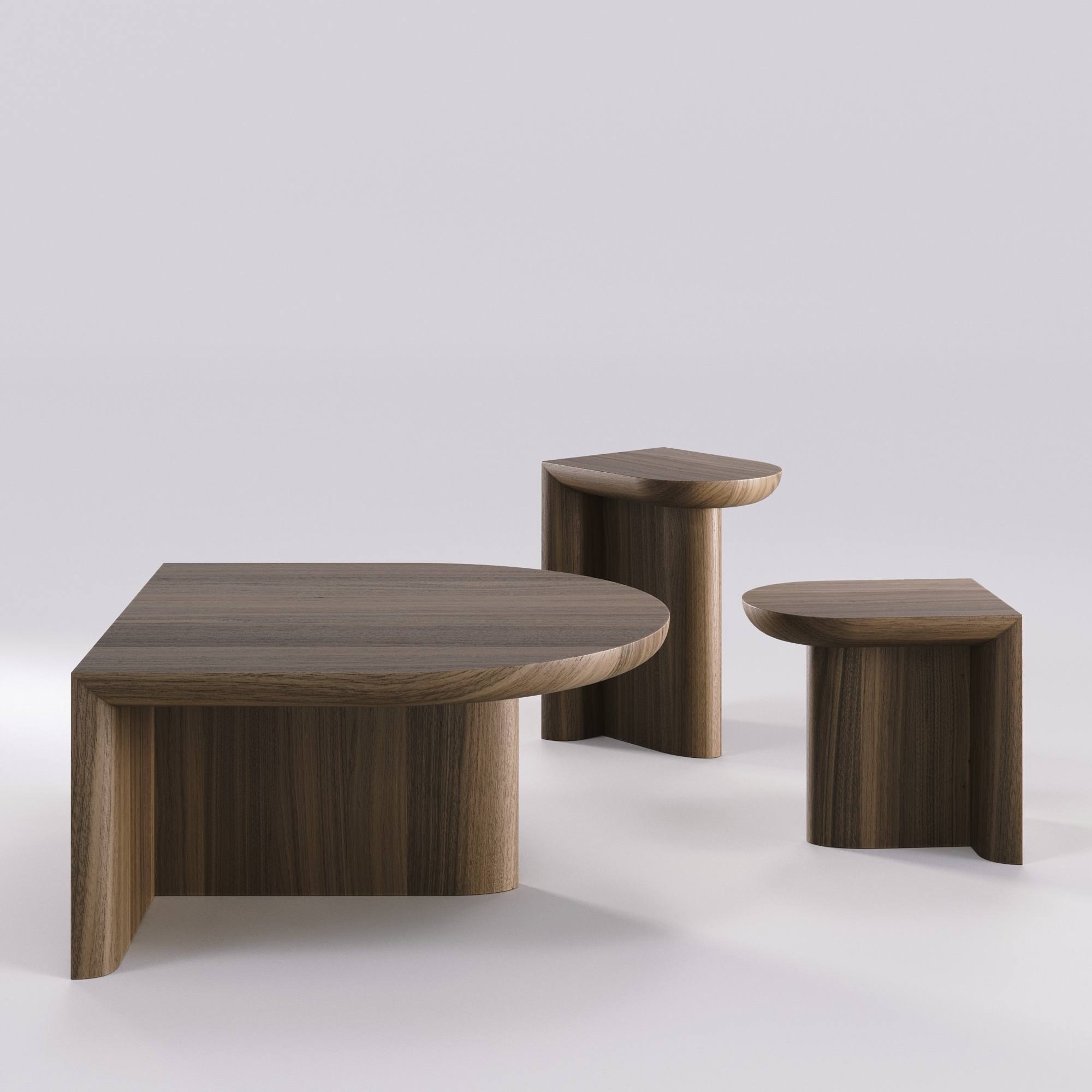 Vue sur fond neutre du trio de tables Re‑Form en noyer massif : une table basse et deux tables d’appoint aux hauteurs différentes.