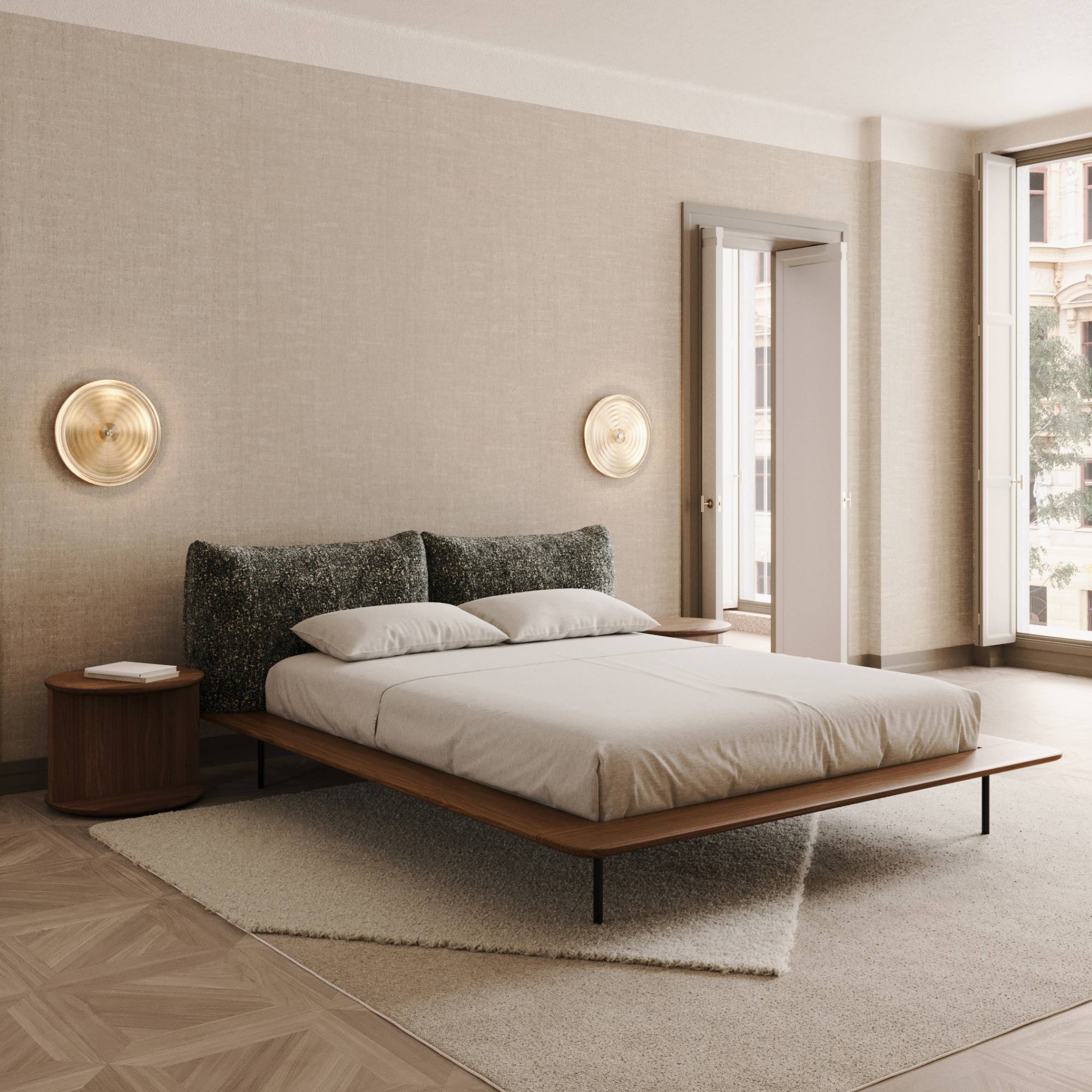 Chambre lumineuse avec lit bas en bois, murs beiges et table d’appoint ronde assortie sur sol parquet et tapis clair