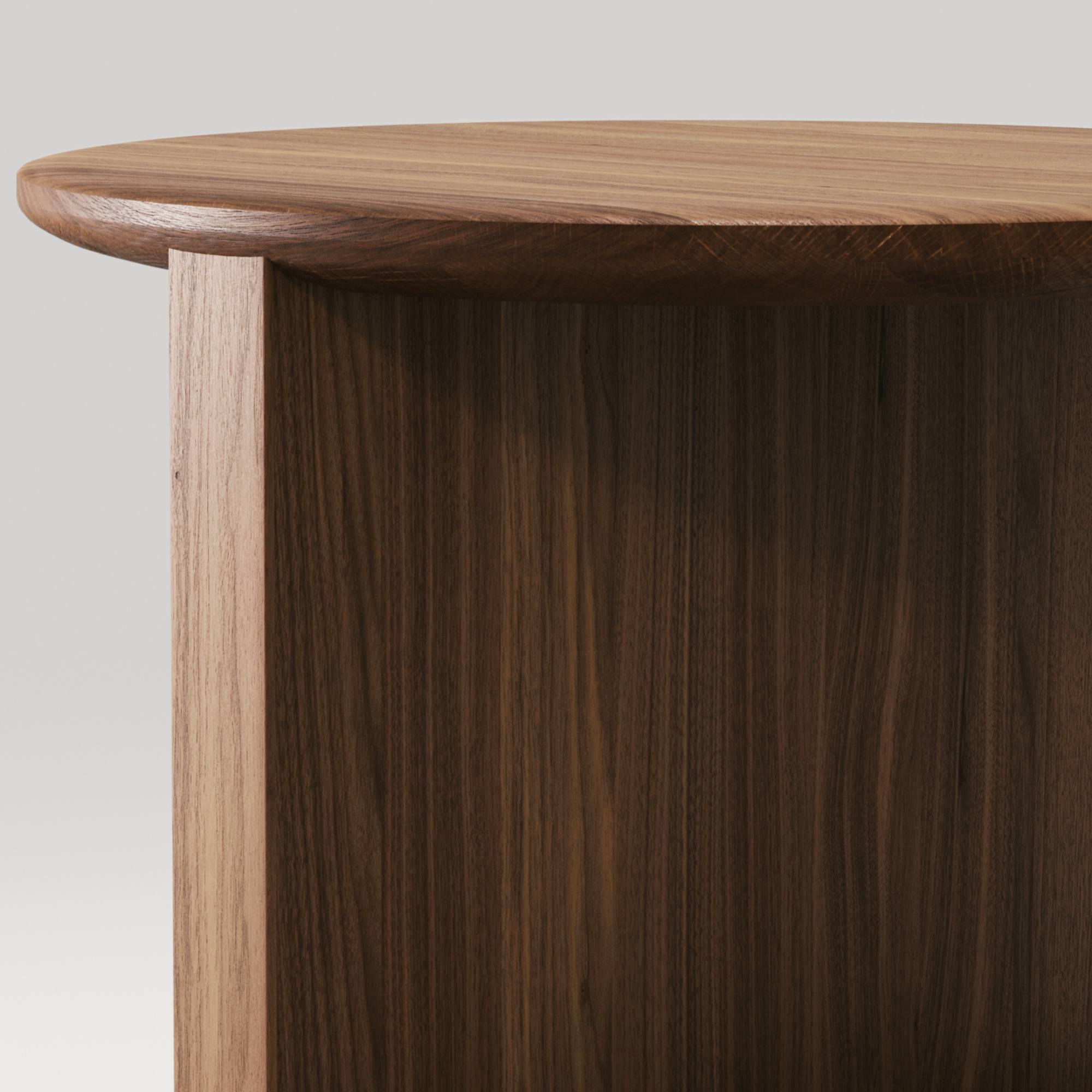 Zoom sur le plateau arrondi en noyer massif et les finitions soignées de la table Duplex