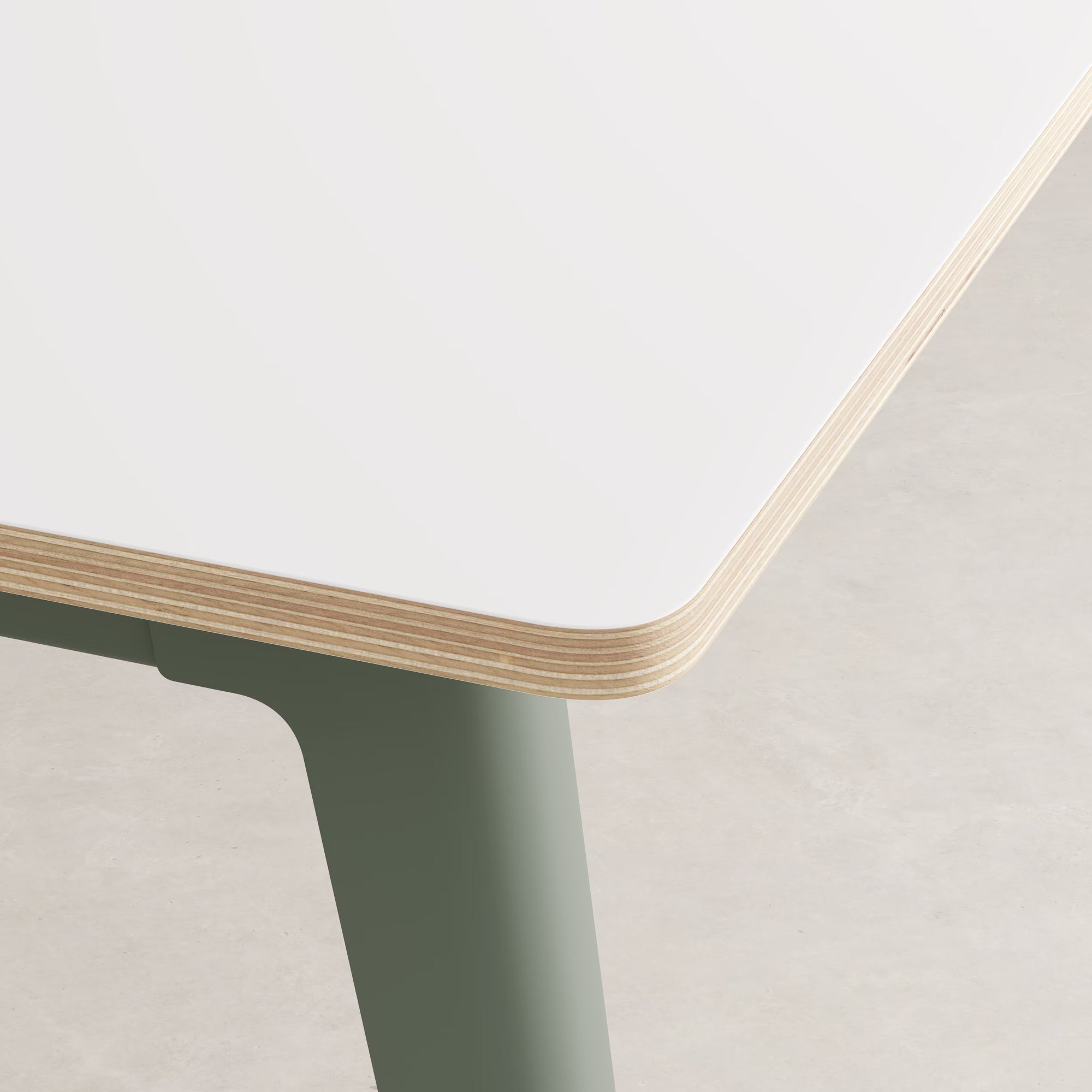 Gros plan sur l’angle d’un bureau stratifié blanc Tiptoe, montrant la tranche en bois multiplis et le piètement gris eucalyptus