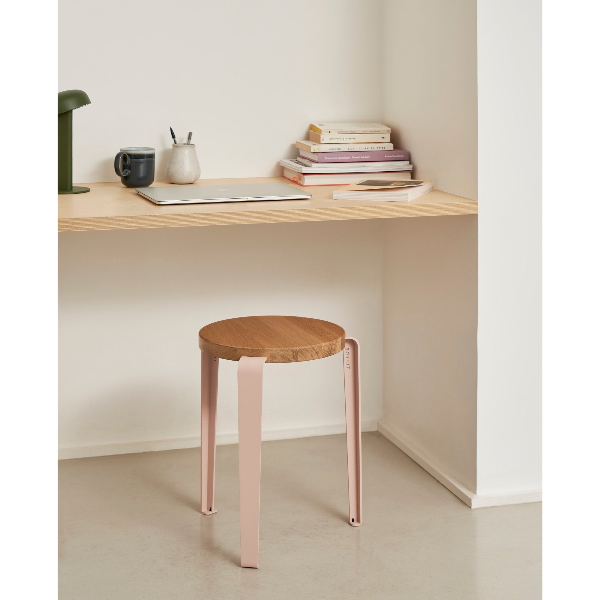 Tabouret Lou en chêne massif et acier rose, placé sous un bureau en bois clair dans un coin lecture ou télétravail lumineux.