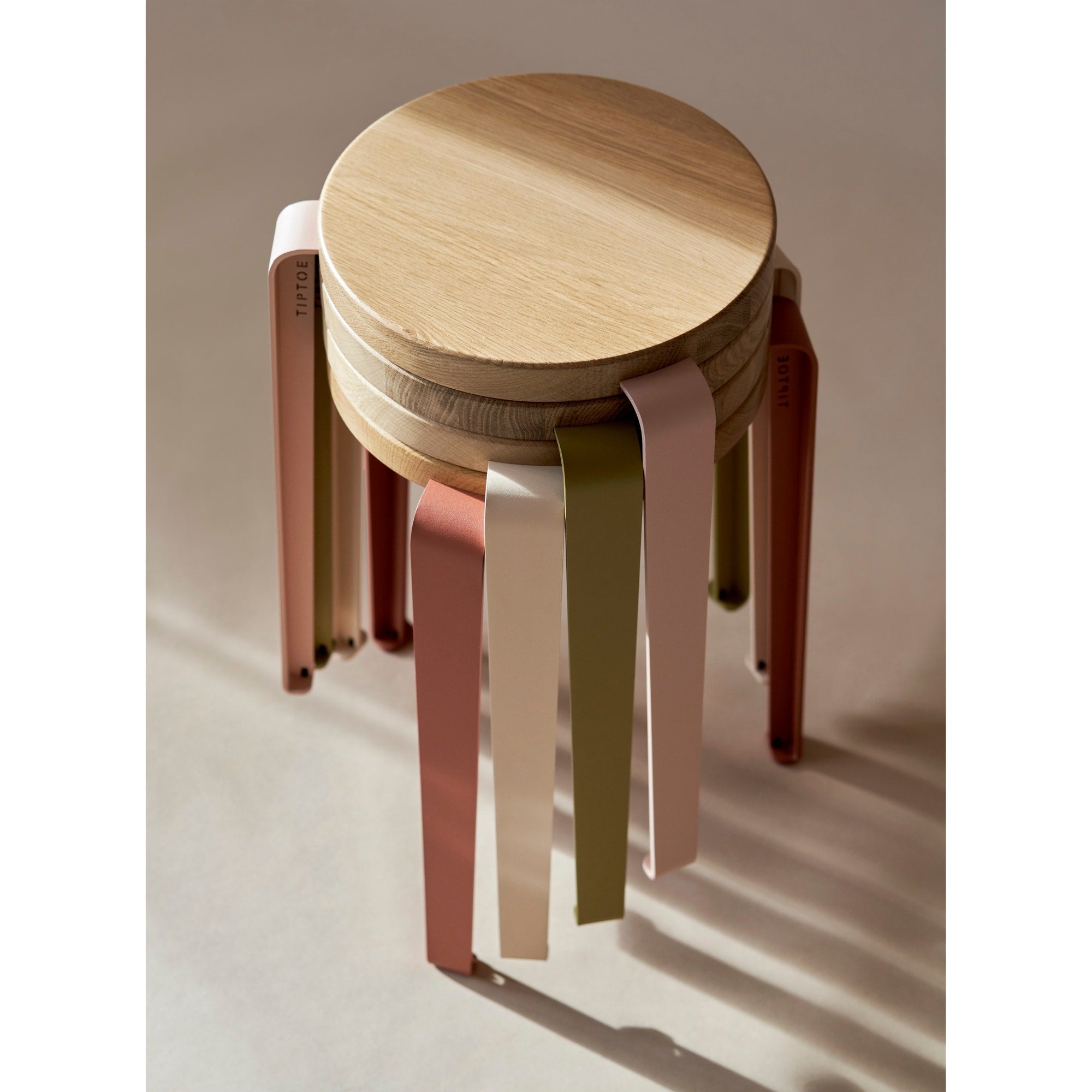 Tabourets Lou empilés, chêne massif et acier coloré, édition Tiptoe x Heju, sur fond beige aux ombres douces.
