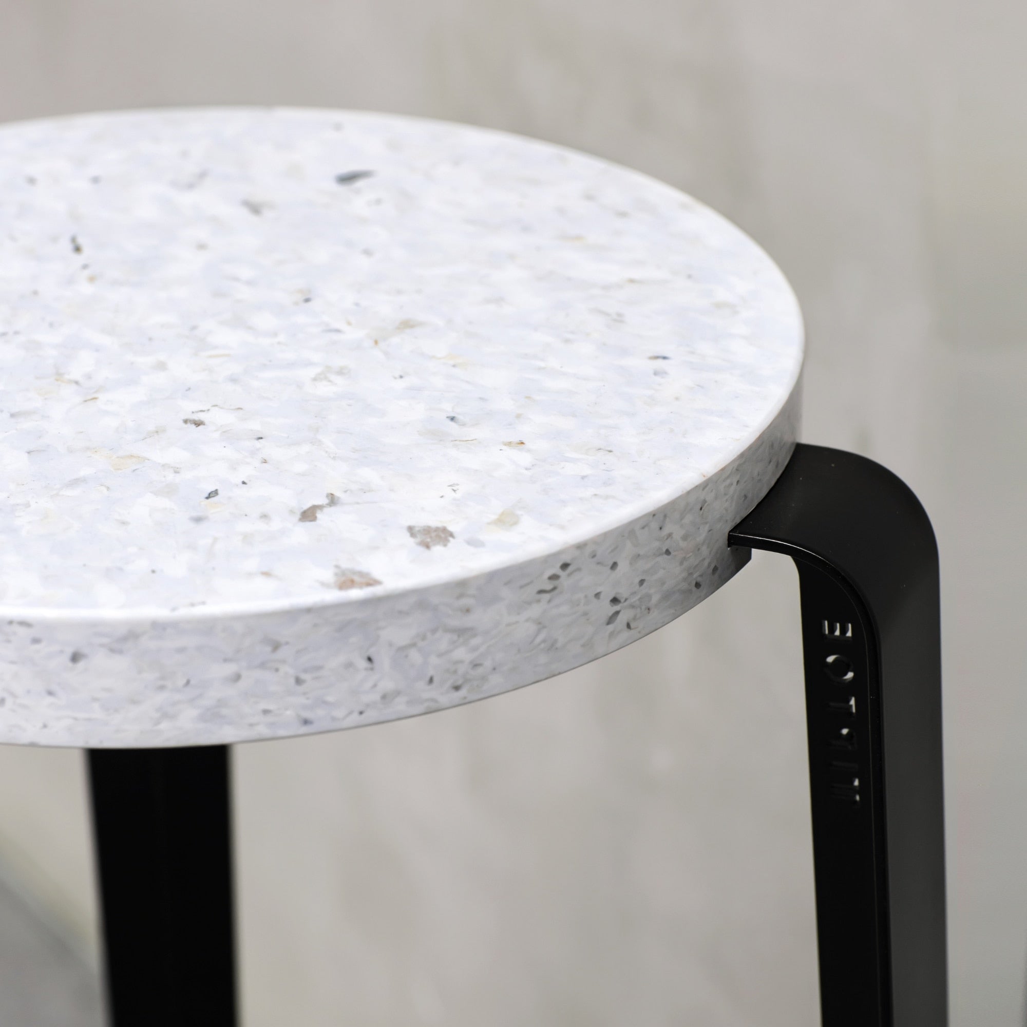 Zoom sur l’assise du tabouret Lou en plastique recyclé blanc moucheté et pieds en acier noir