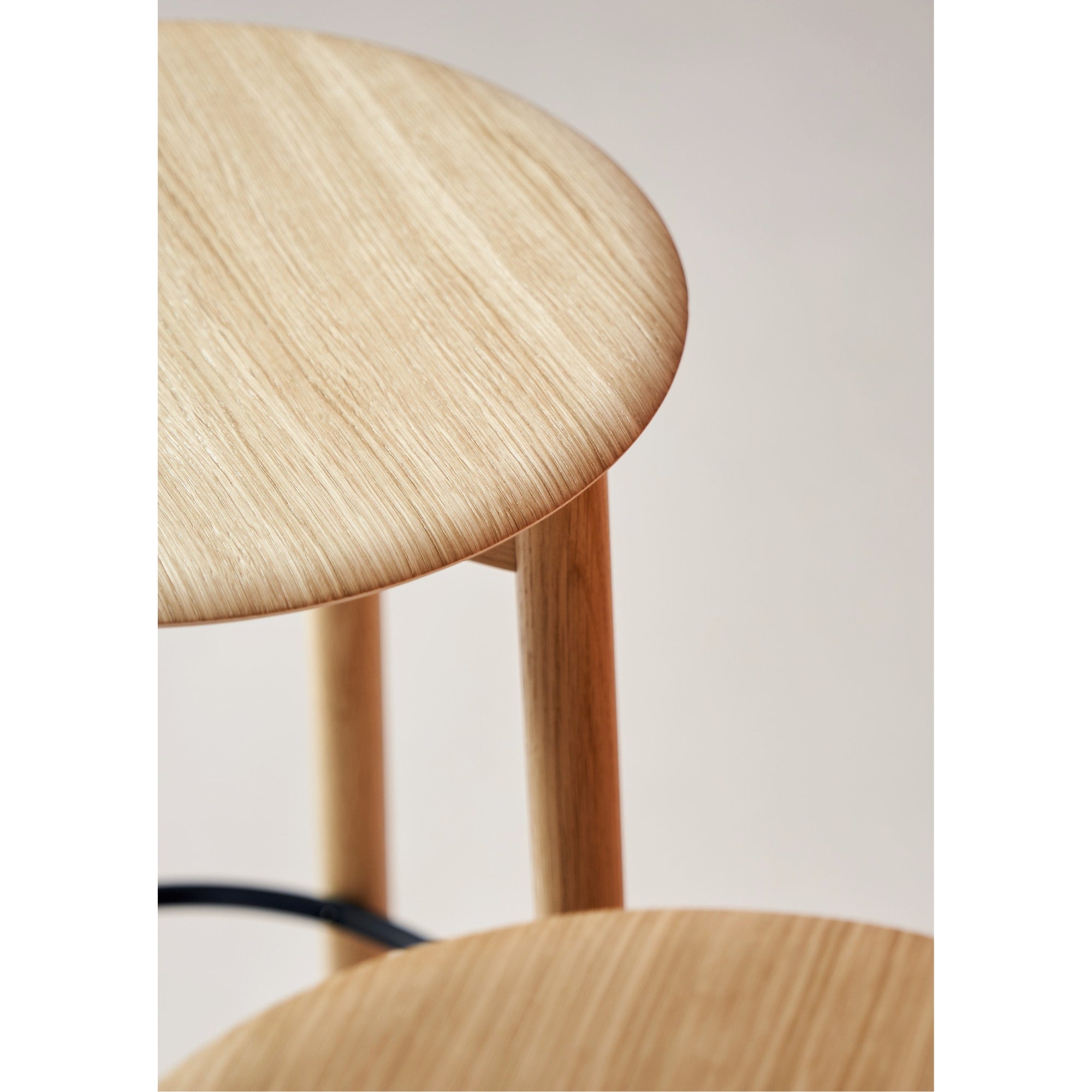 Zoom sur l’assise en bois clair et le piètement en bois du tabouret de bar SSD Tiptoe, avec repose-pieds noir.