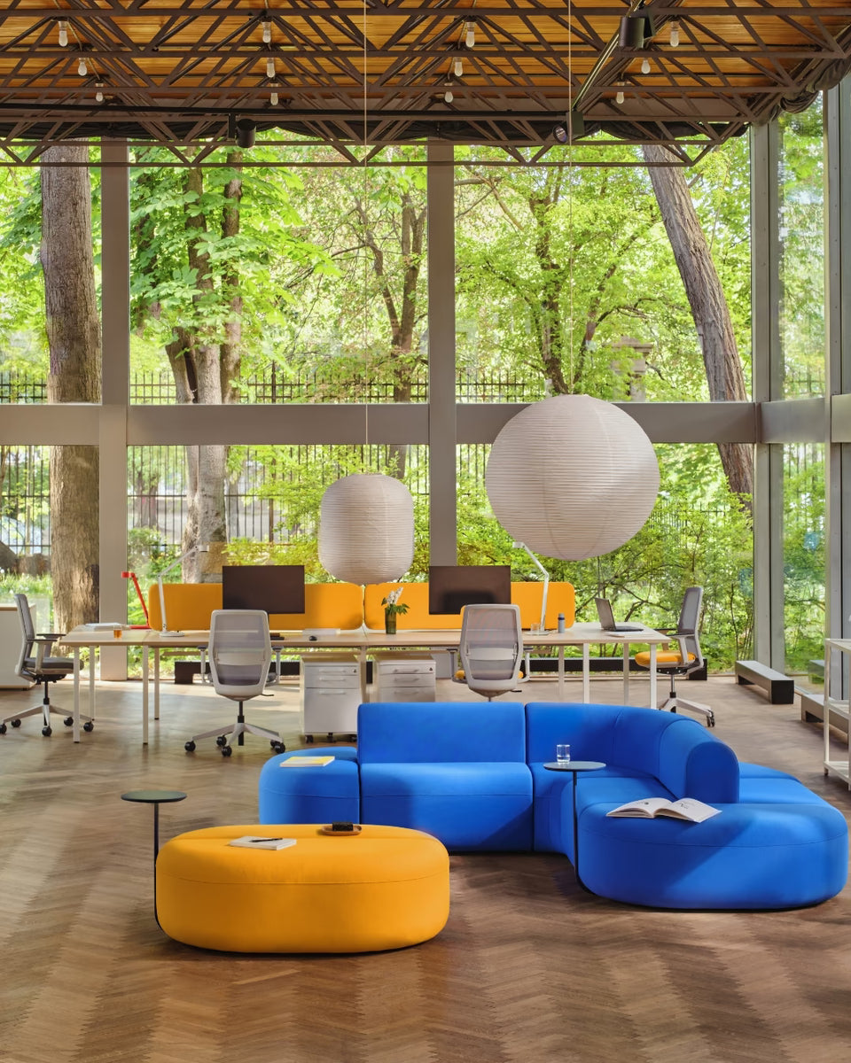 Banquette colorée en tissu pour open space avec bureaux partagés et assises ergonomiques, conçue par MDD, idéale pour créer une zone détente en milieu professionnel.