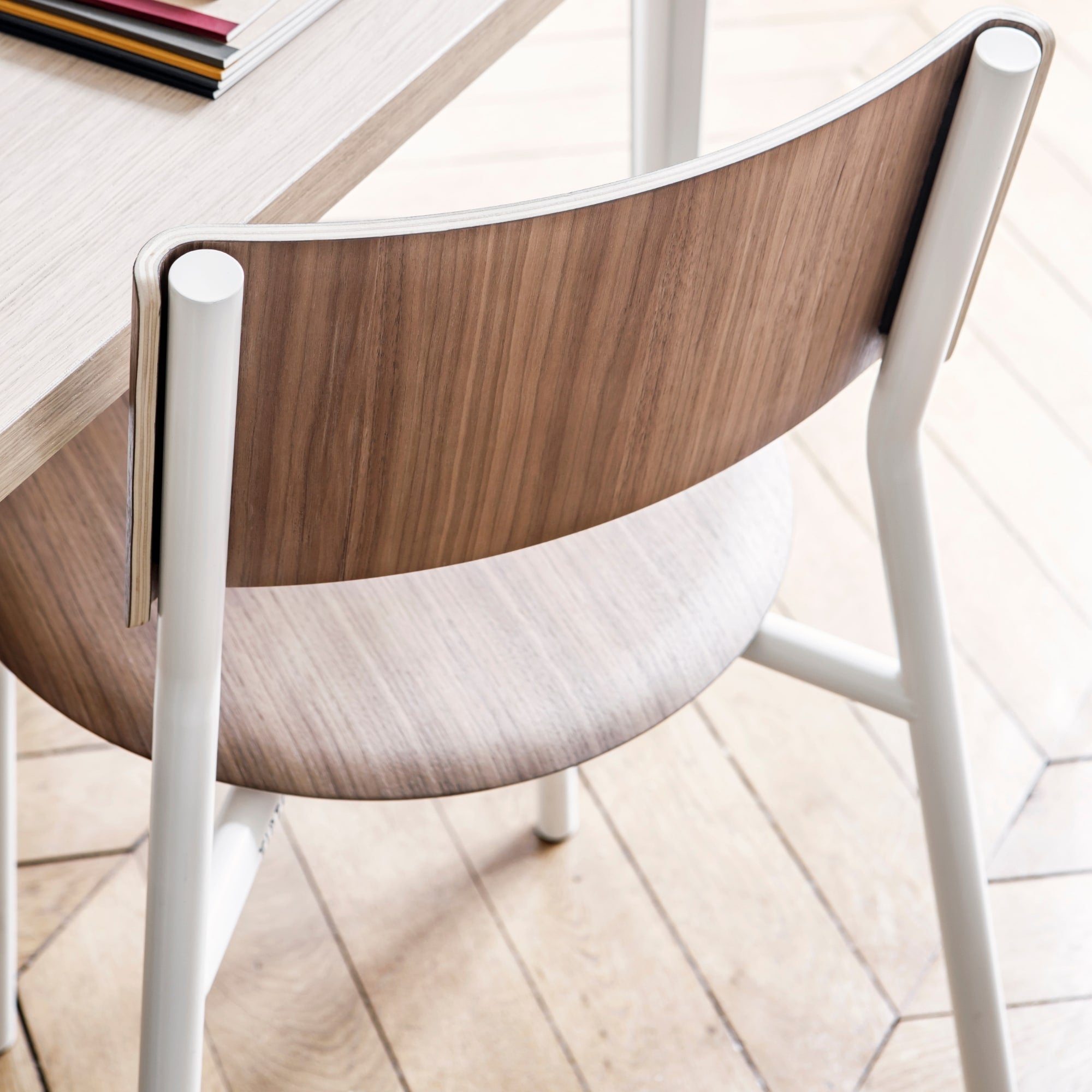 Chaise en noyer et acier, modèle SSD de Tiptoe, avec structure blanche et assise en bois clair, vue en gros plan sur le dossier et la jonction avec les pieds.