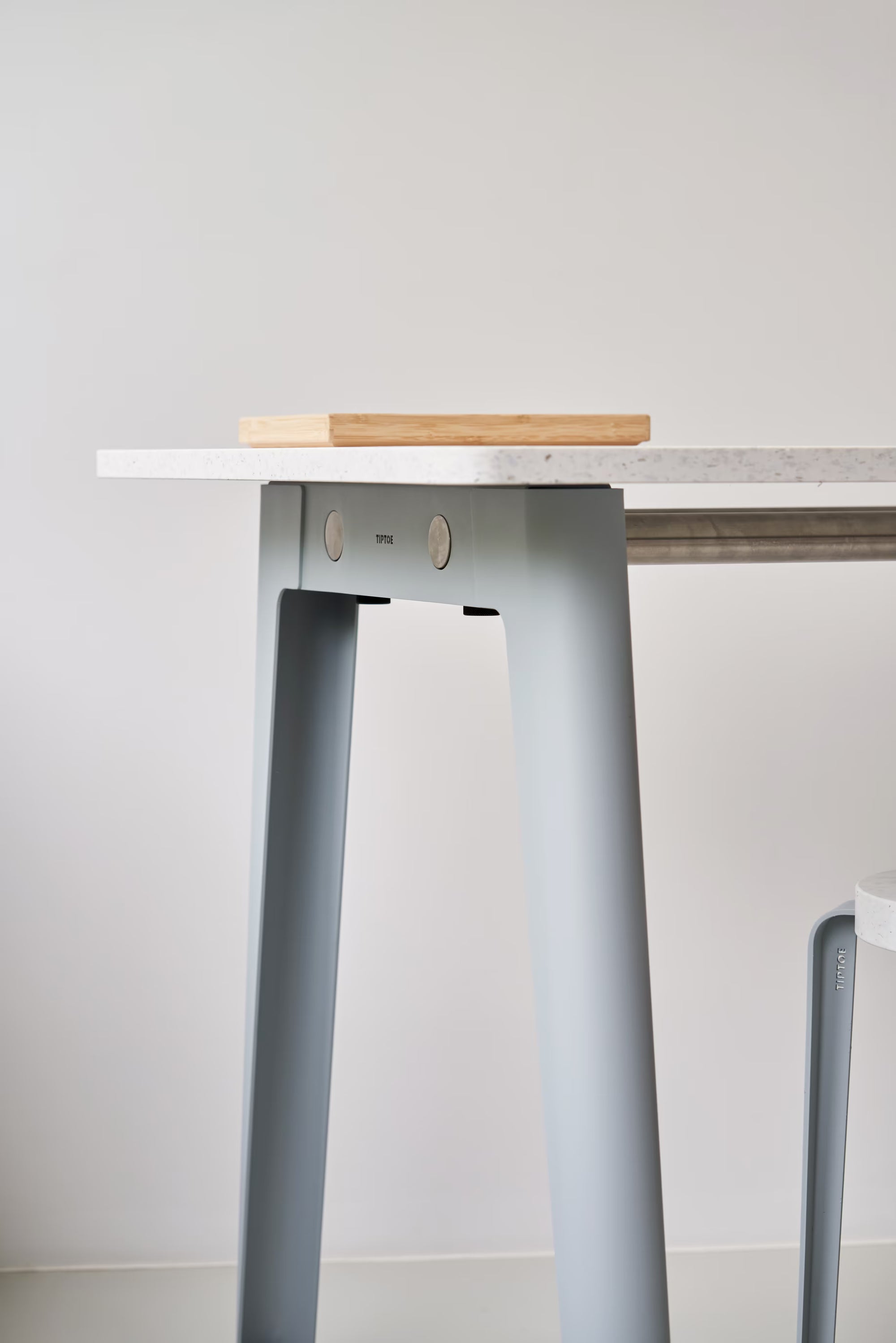 Détail du bureau New Modern Tiptoe avec plateau en plastique recyclé blanc et piètement bleu clair vu de côté.