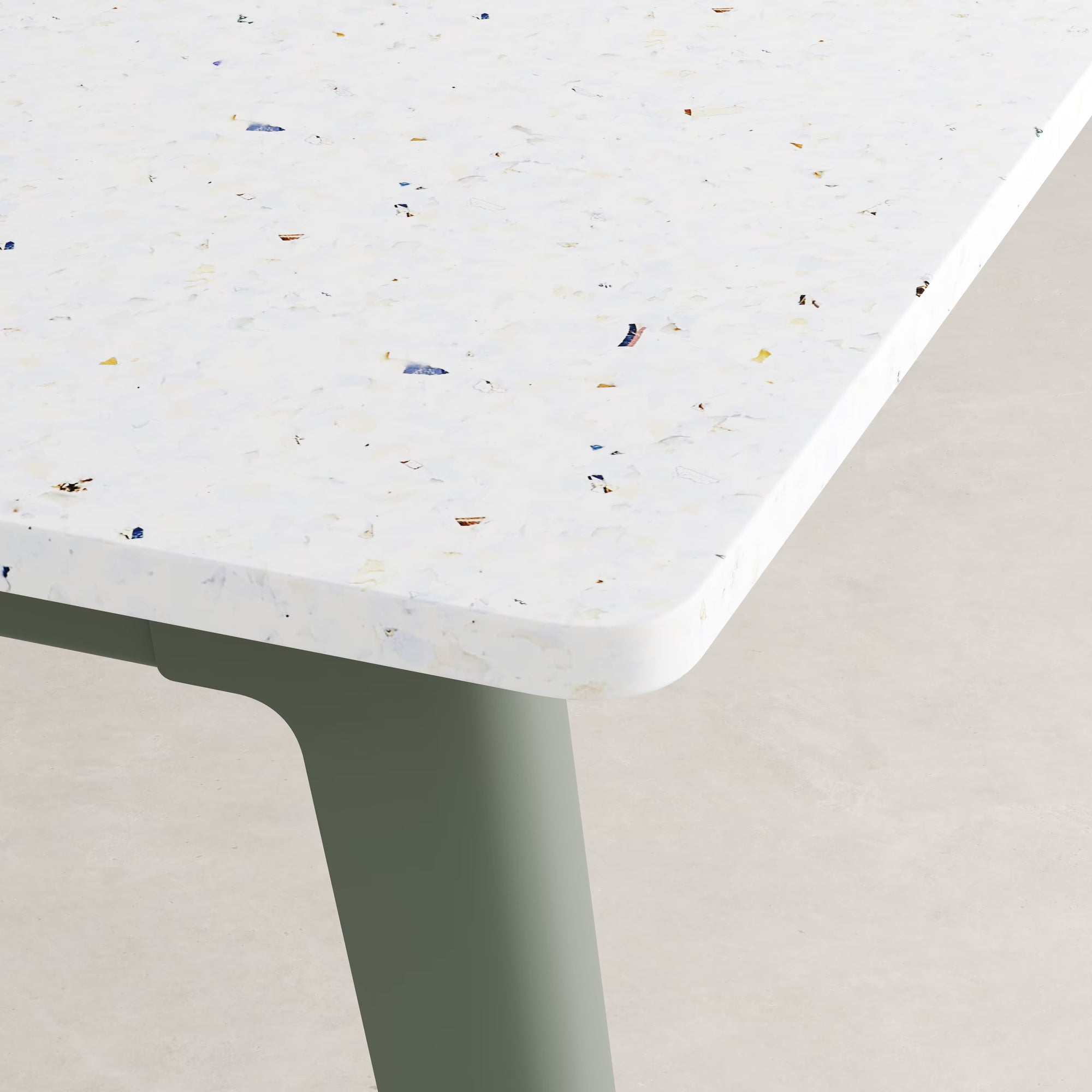 Gros plan sur un plateau blanc en plastique recyclé, éclats colorés façon terrazzo, sur piètement gris eucalyptus.
