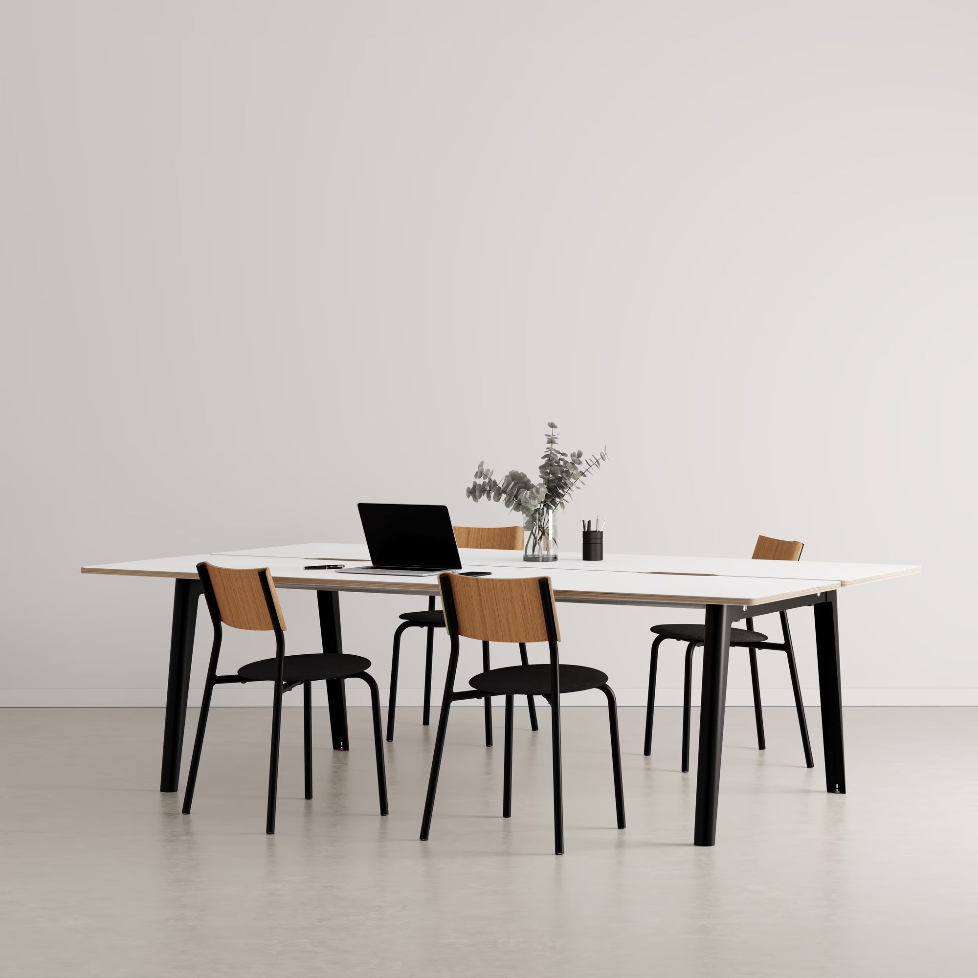 Bureau partagé rectangulaire en bois clair avec pieds noirs, présenté avec chaises assorties et accessoires sur fond neutre