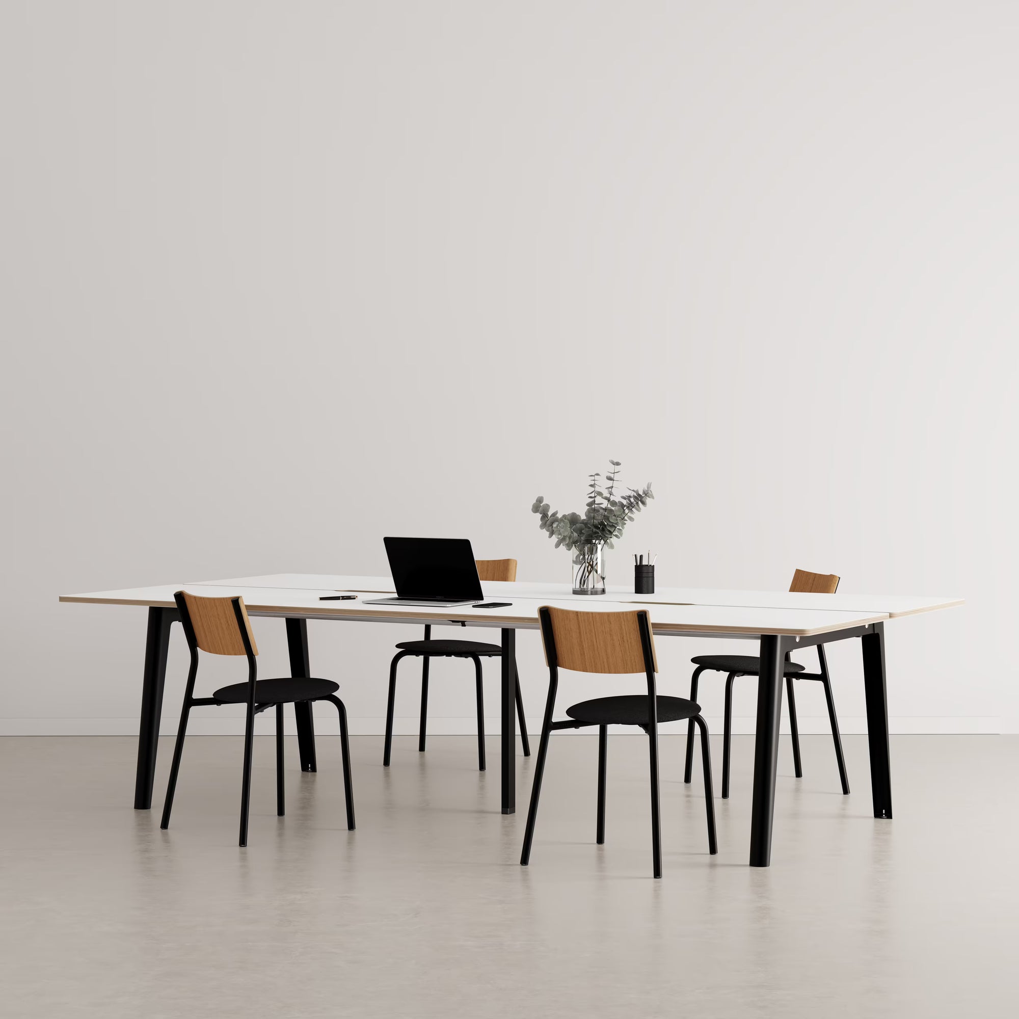 Bureau partagé rectangulaire en bois clair avec pieds noirs, présenté avec chaises assorties et accessoires sur fond neutre