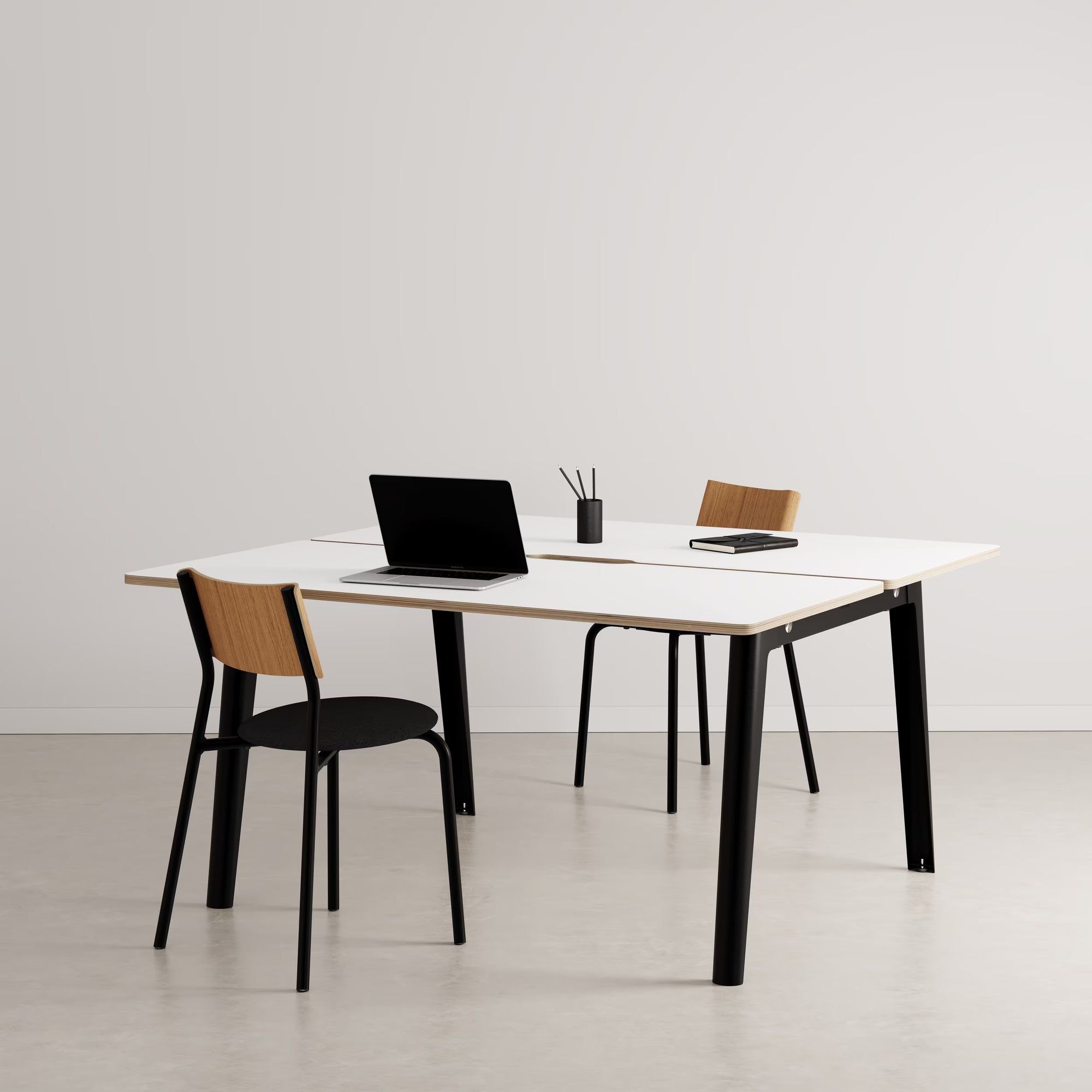 Bureau partagé rectangulaire plateau clair avec pieds noirs, présenté avec chaises assorties et accessoires sur fond neutre