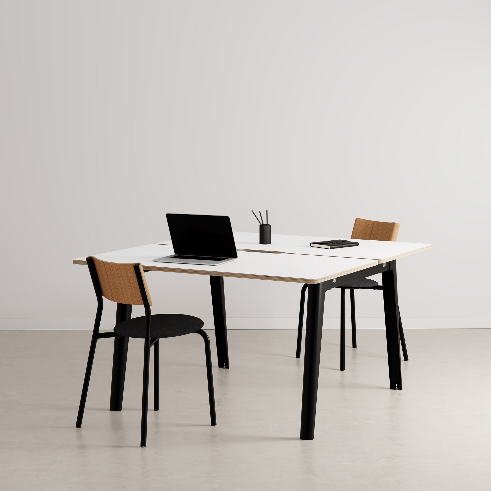 Bureau partagé rectangulaire plateau clair avec pieds noirs, présenté avec chaises assorties et accessoires sur fond neutre