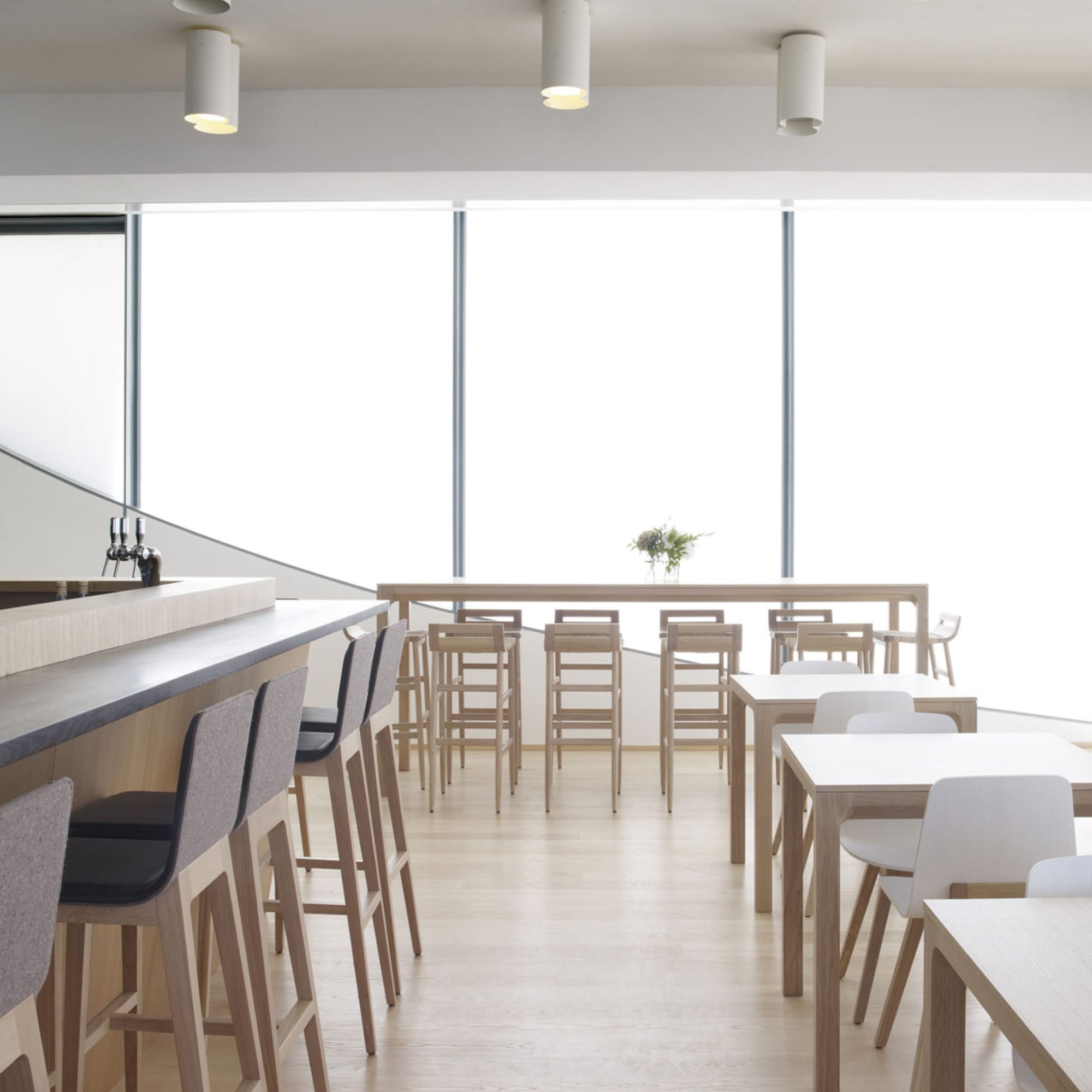 Tabourets Kimua 76 cm en chêne et paille signés Alki, alignés devant un comptoir dans un restaurant minimaliste