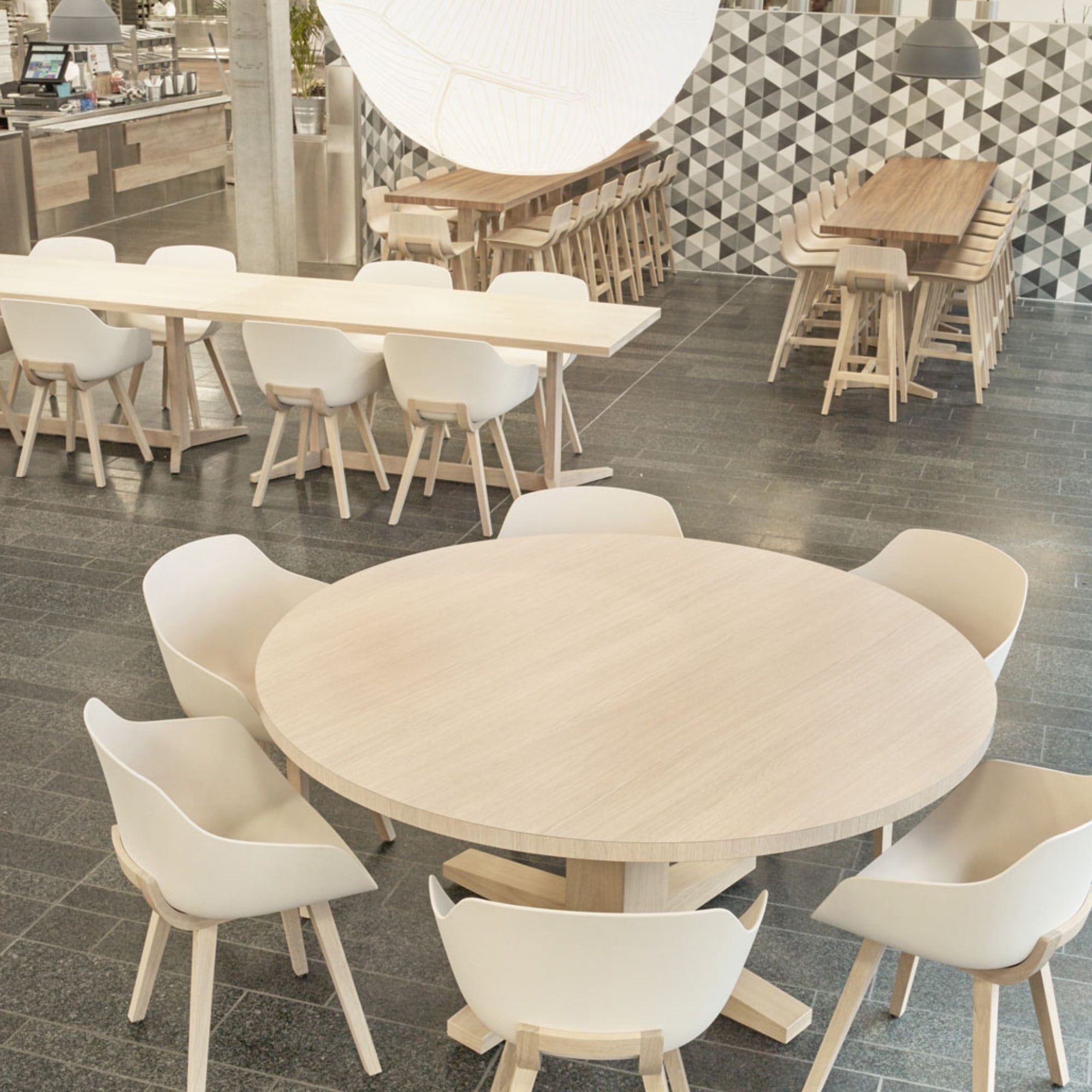 Salle de restaurant avec chaises Kuskoa Bi blanches et pieds bois clair autour de tables rondes et rectangulaires