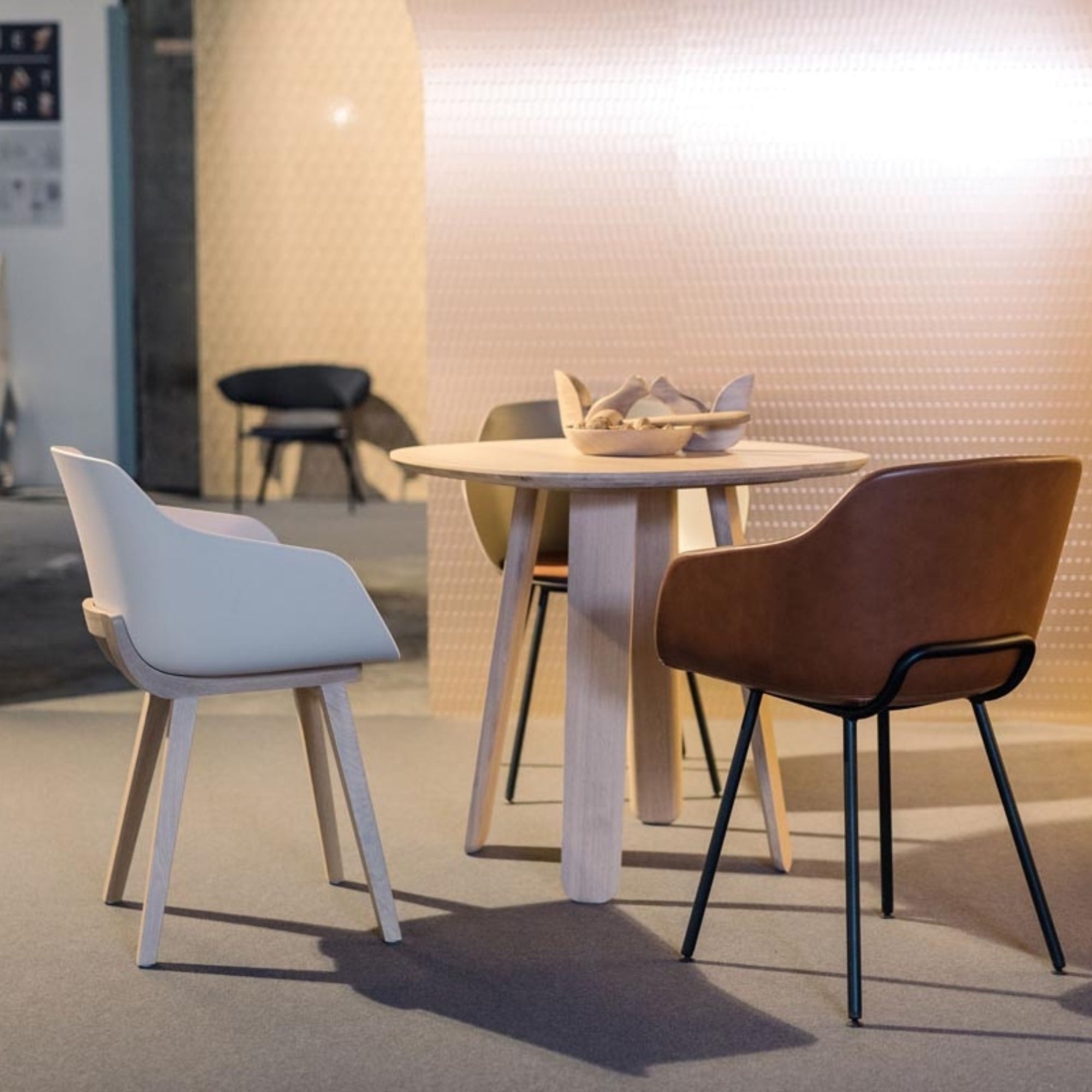 Trois chaises Kuskoa Bi en bioplastique et bois ou métal disposées autour d’une table ronde en bois clair.