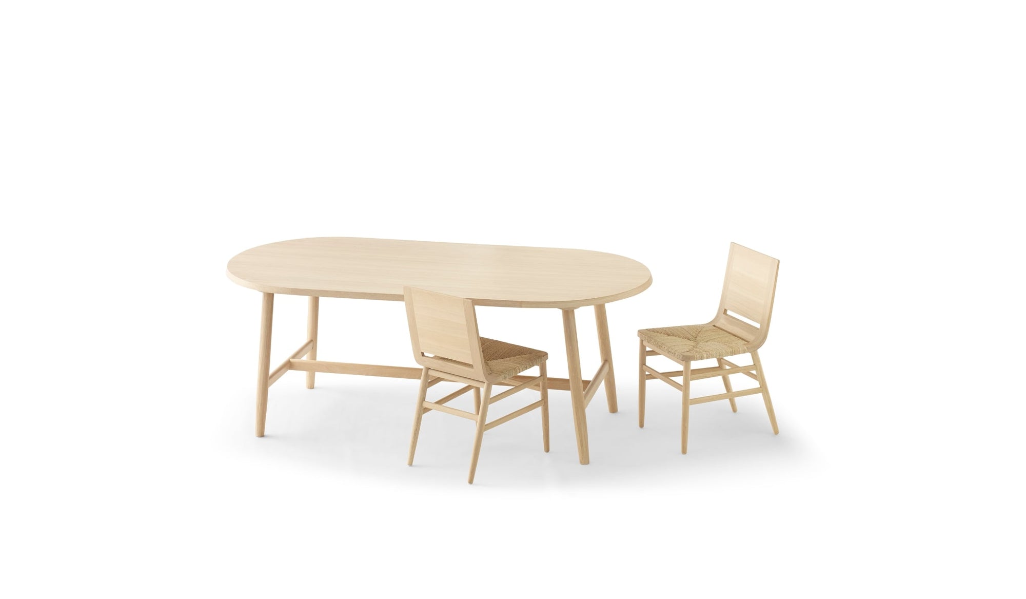 Chaises Kimua en chêne avec assise en paille de la marque Alki, disposées autour d’une table ovale assortie, sur fond blanc