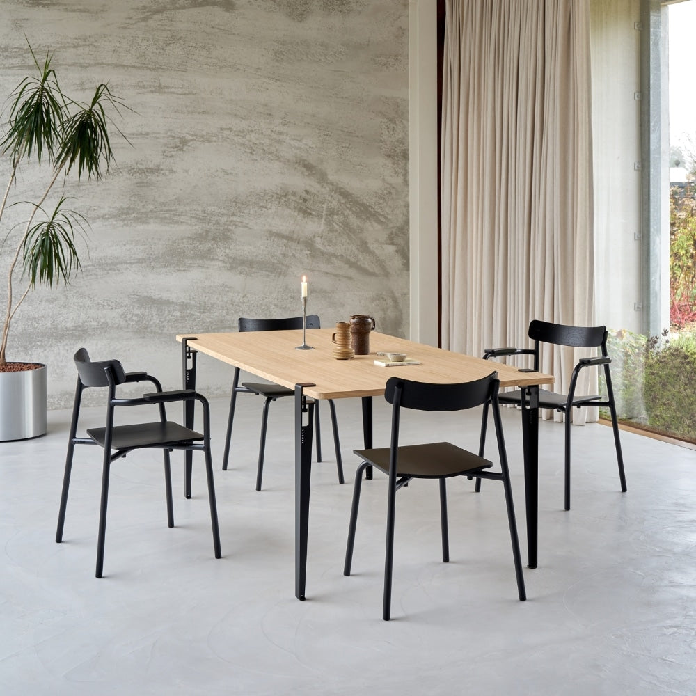 Salle à manger avec plusieurs chaises en bois et métal autour de tables dans un espace lumineux.