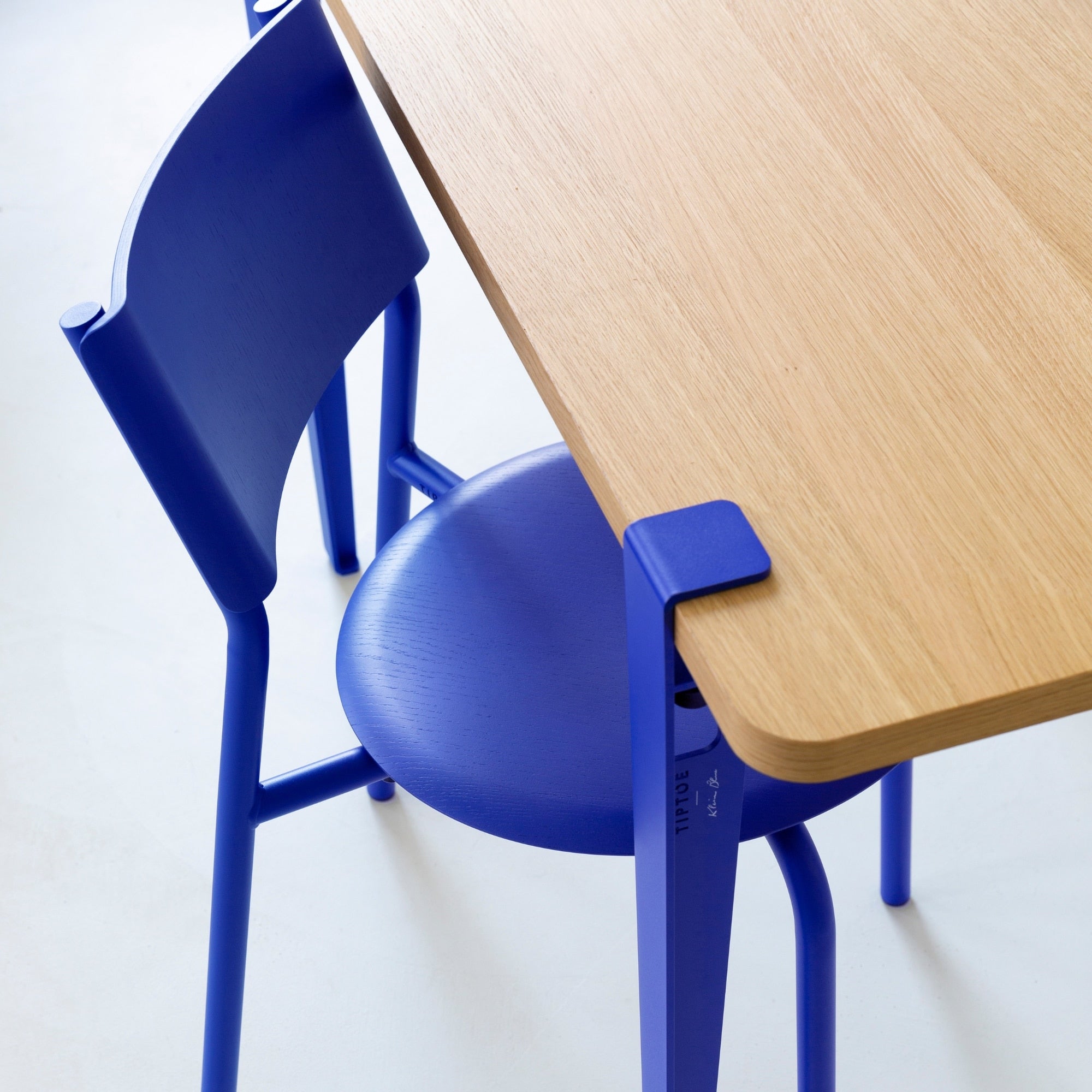 Chaise SSD Tiptoe en bleu Klein associée à une table en bois clair, vue rapprochée sur l’assise et la fixation en métal.
