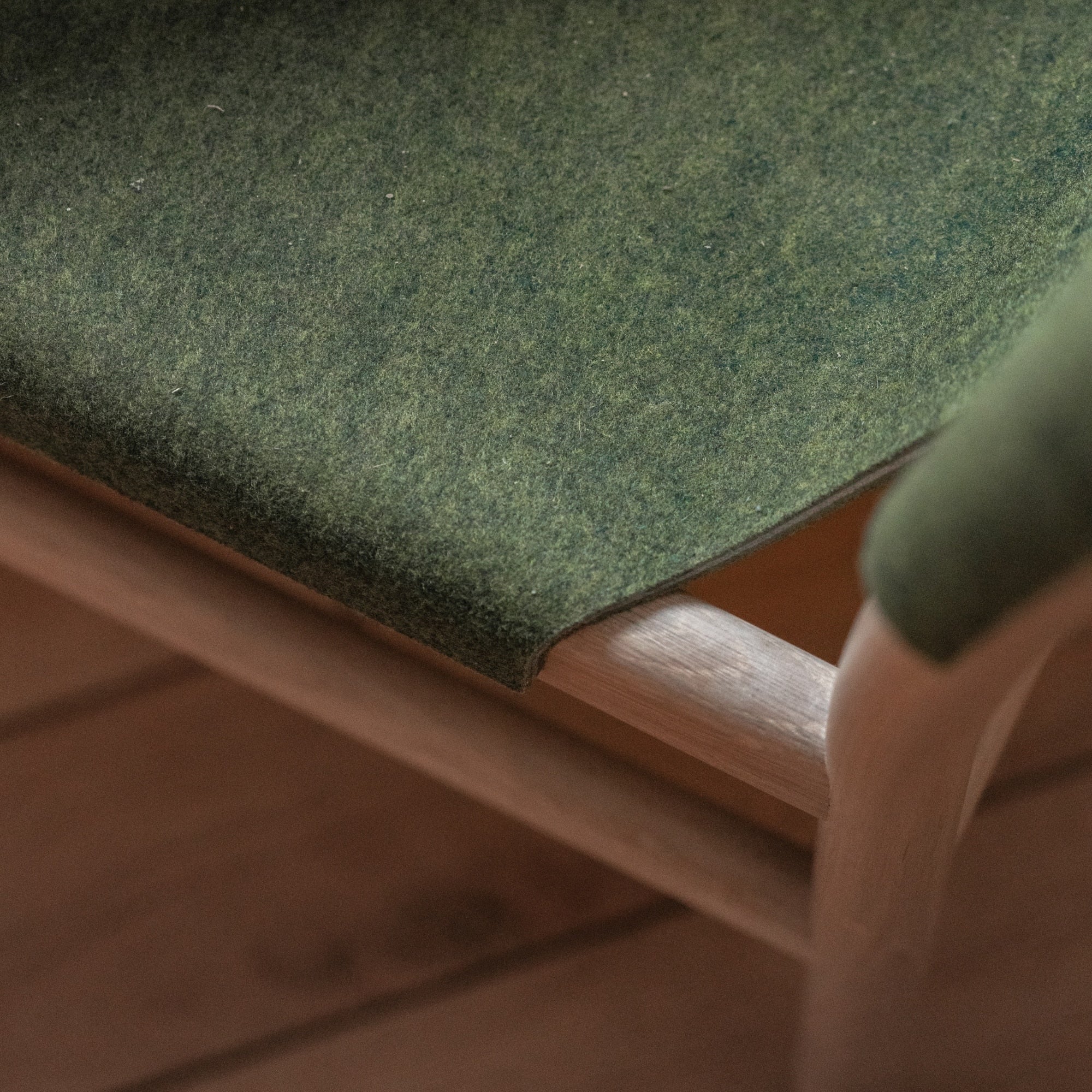 Détail d’une assise en tissu vert sur structure en bois clair, chaise design Xume de la marque Alki