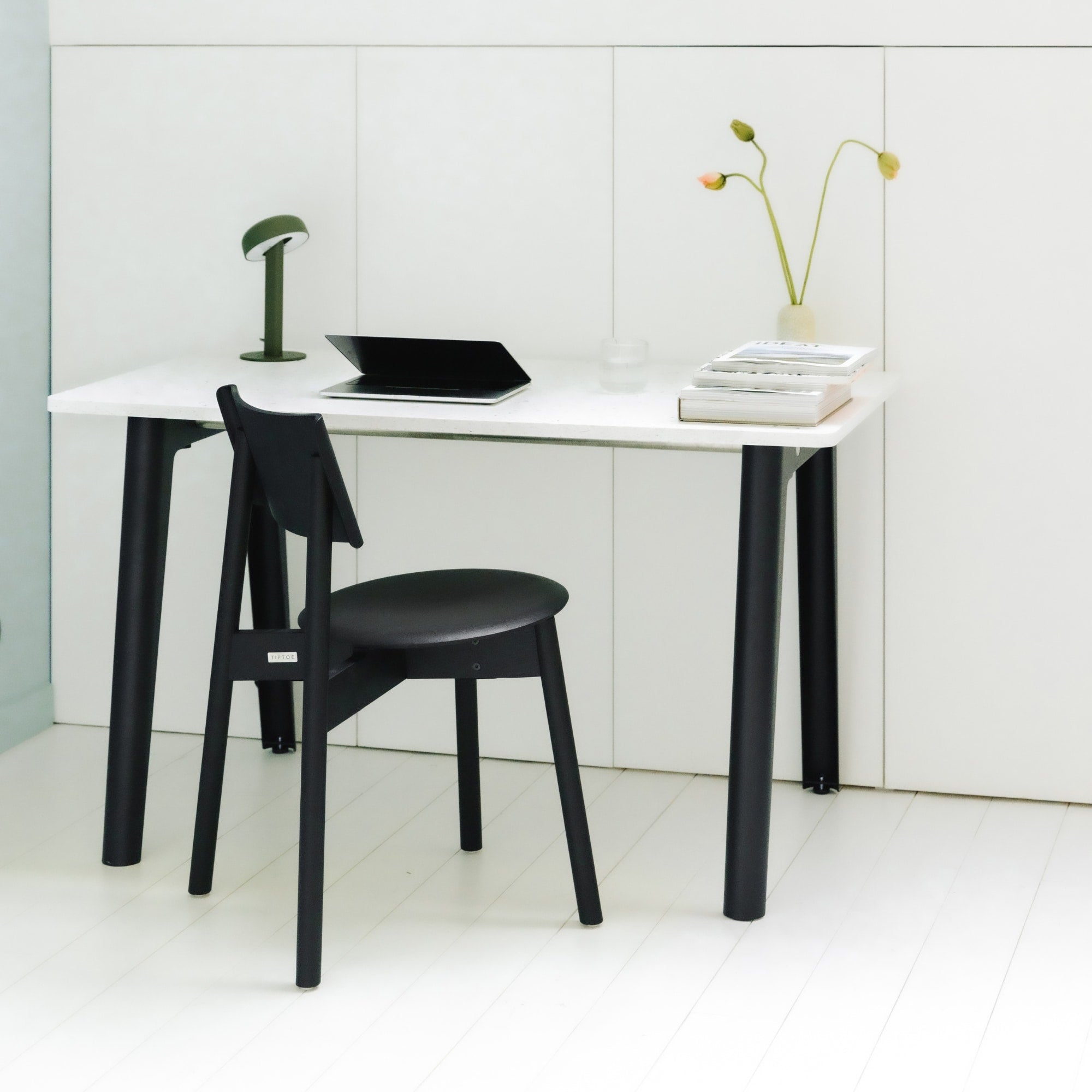 Chaise SSD Full Wood de Tiptoe en chêne teinté noir, associée à un bureau blanc minimaliste aux pieds noirs, dans un espace de travail lumineux et épuré.
