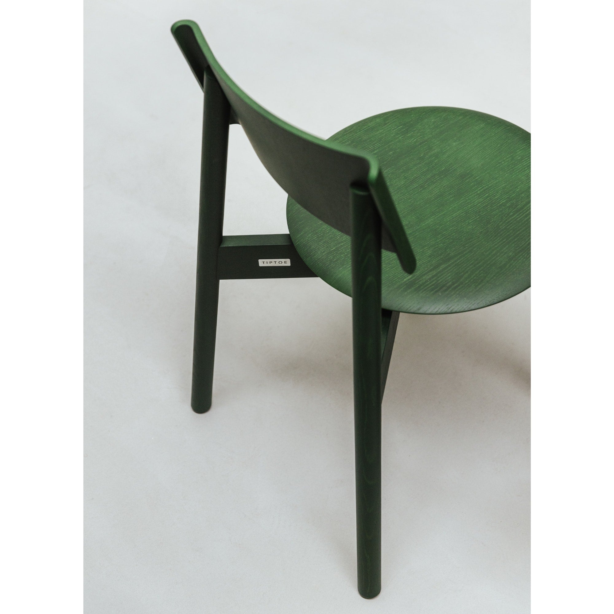 Vue arrière d’une chaise SSD Full Wood de Tiptoe en chêne teinté vert, mettant en valeur la courbe du dossier et les détails du bois.