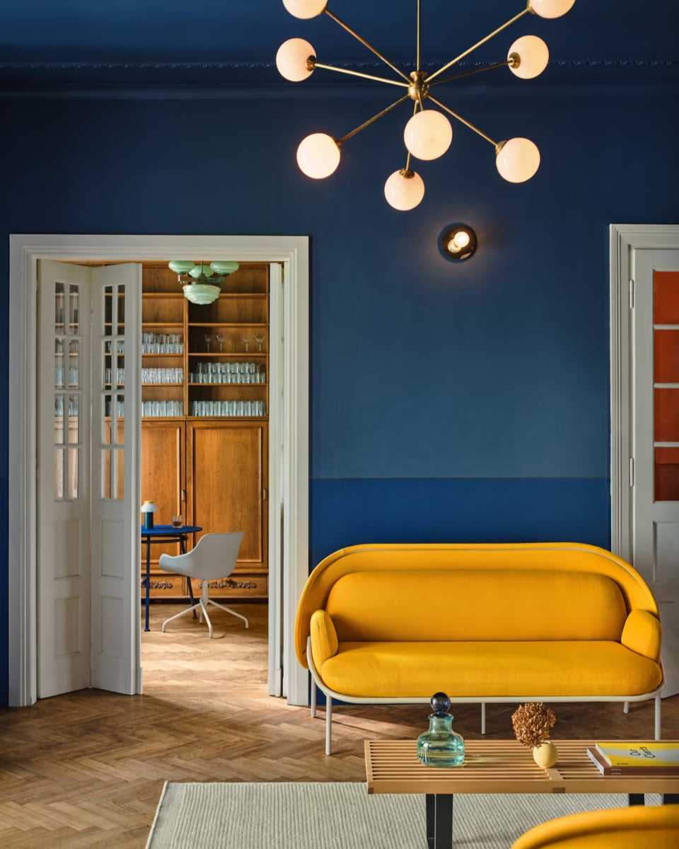 Canapé design jaune dans un espace détente de bureau, ambiance chaleureuse avec murs bleus et mobilier contemporain signé novinea.