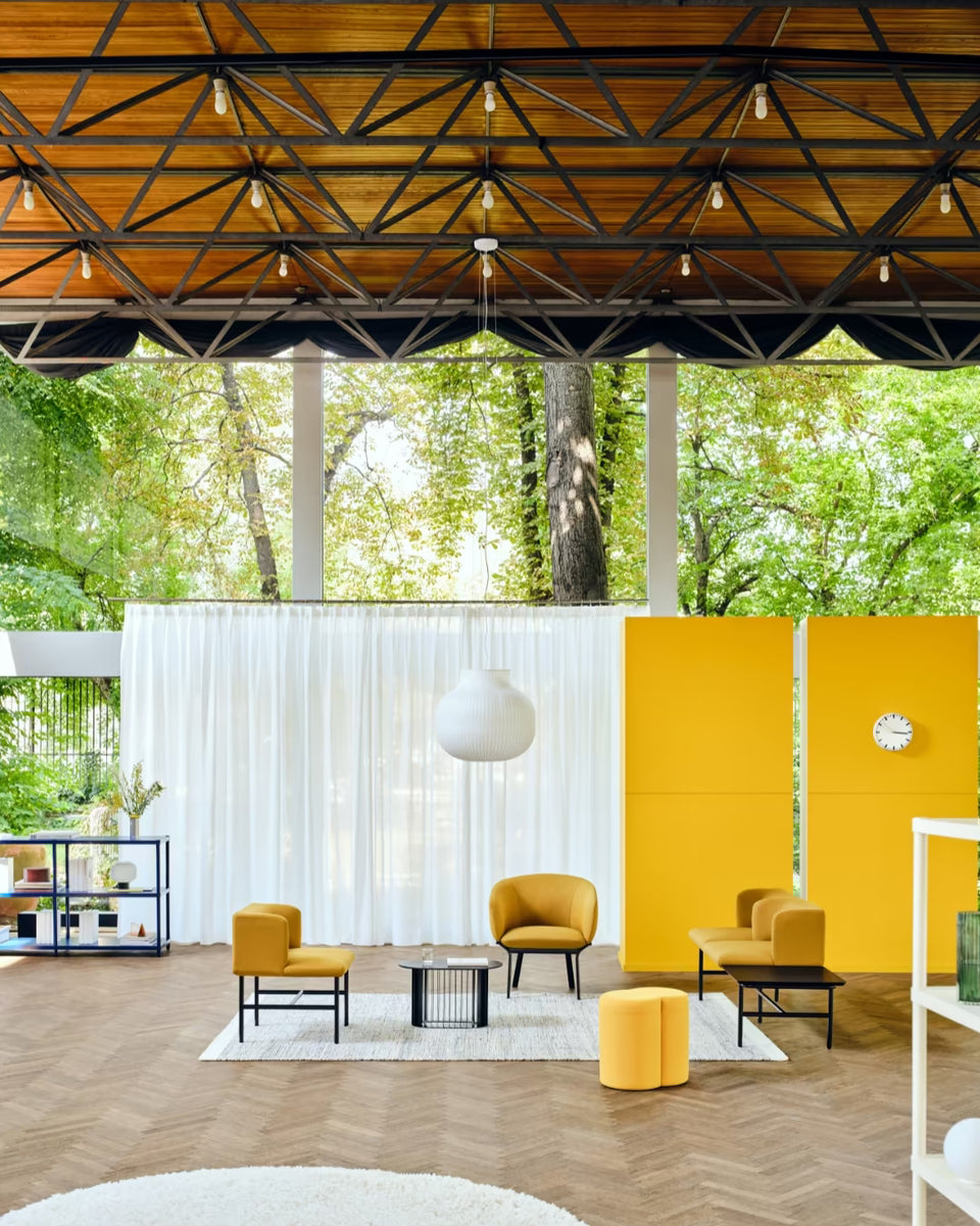 Espace détente coloré en open space avec fauteuils design jaune moutarde, cloison acoustique et mobilier modulable, idéal pour bureaux collaboratifs.