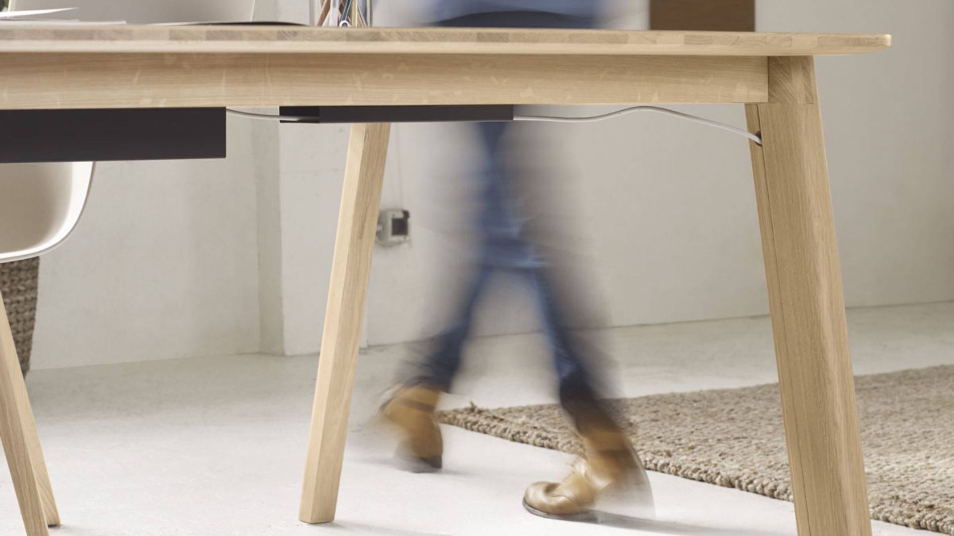 Détail d’un bureau en bois clair dans un espace de travail fluide, illustrant la circulation libre et l’agencement ergonomique du mobilier professionnel.