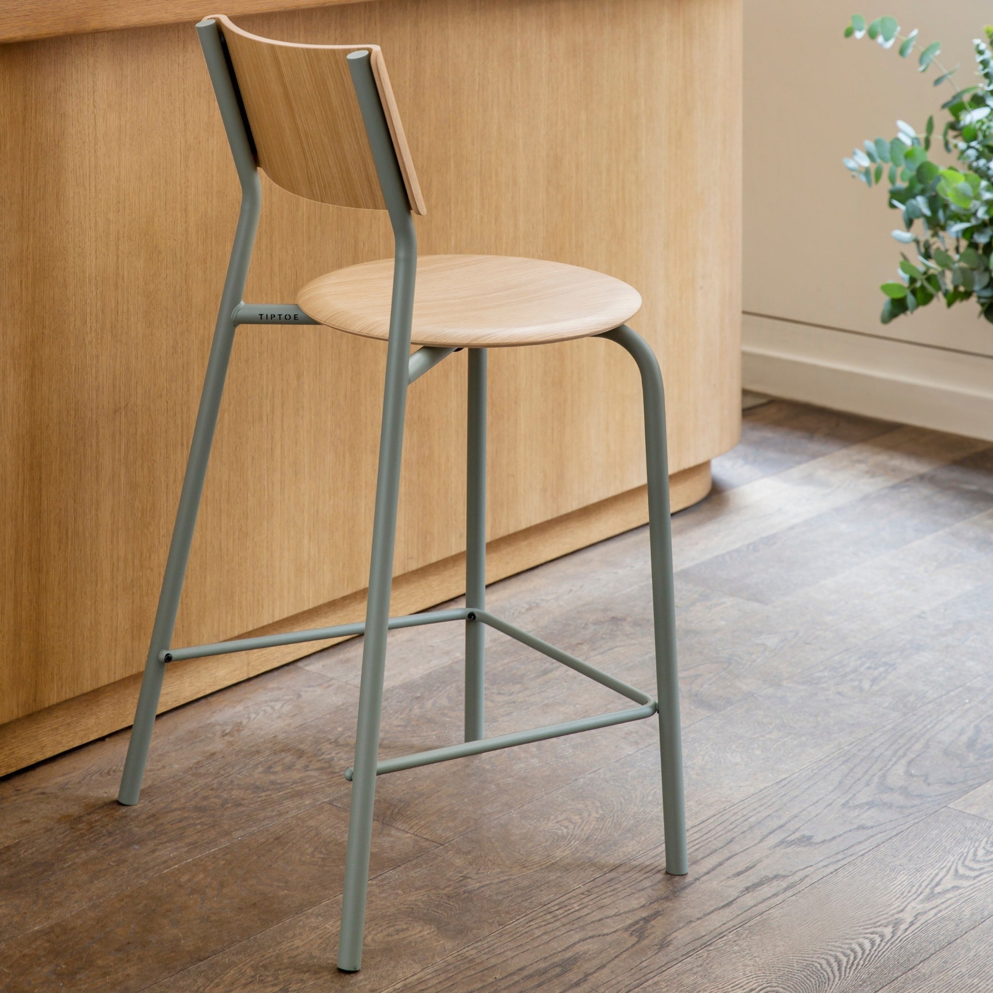 Chaise haute en bois clair avec piètement métallique gris eucalyptus devant un comptoir en bois clair.