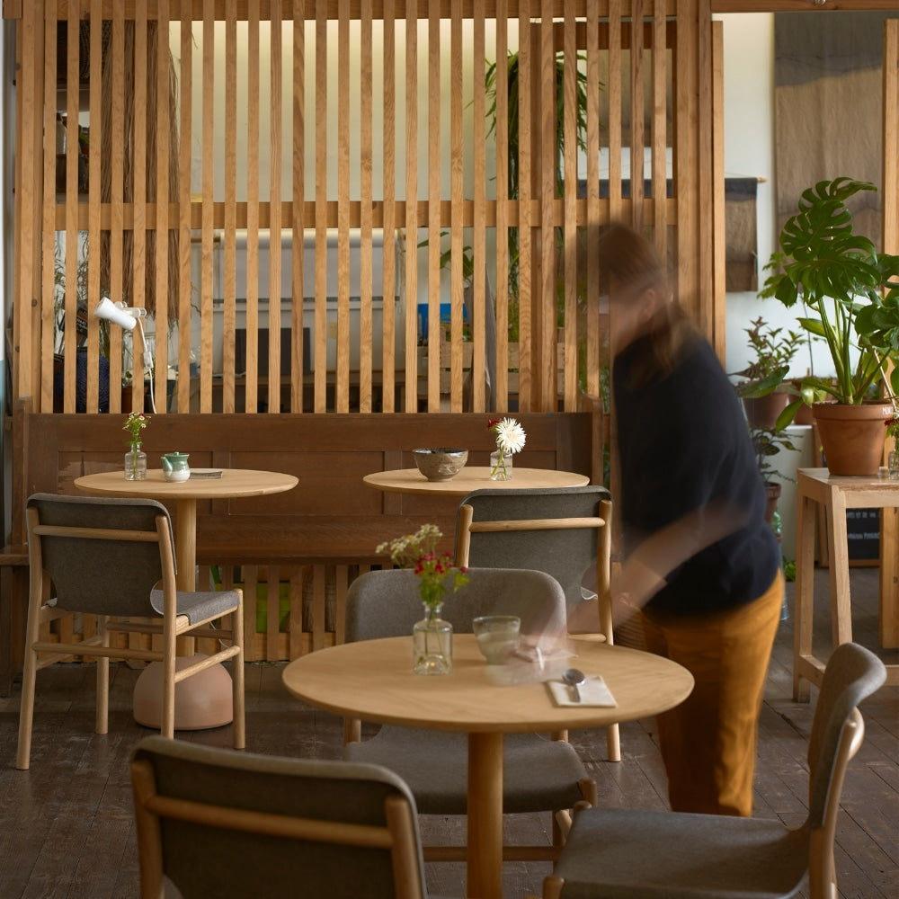 Salle de restaurant avec mobilier en bois et tissu, ambiance chaleureuse et naturelle.