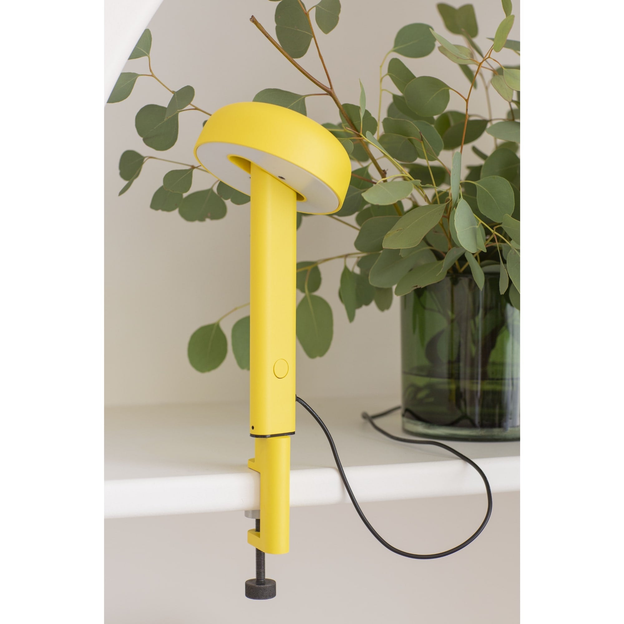 Lampe à pince jaune de design moderne, modèle Nod de Tiptoe, vue de face avec l’éclairage éteint, orienté vers l’avant. Le bras fin soutient un abat-jour circulaire, et le cordon est visible sous la lampe.
