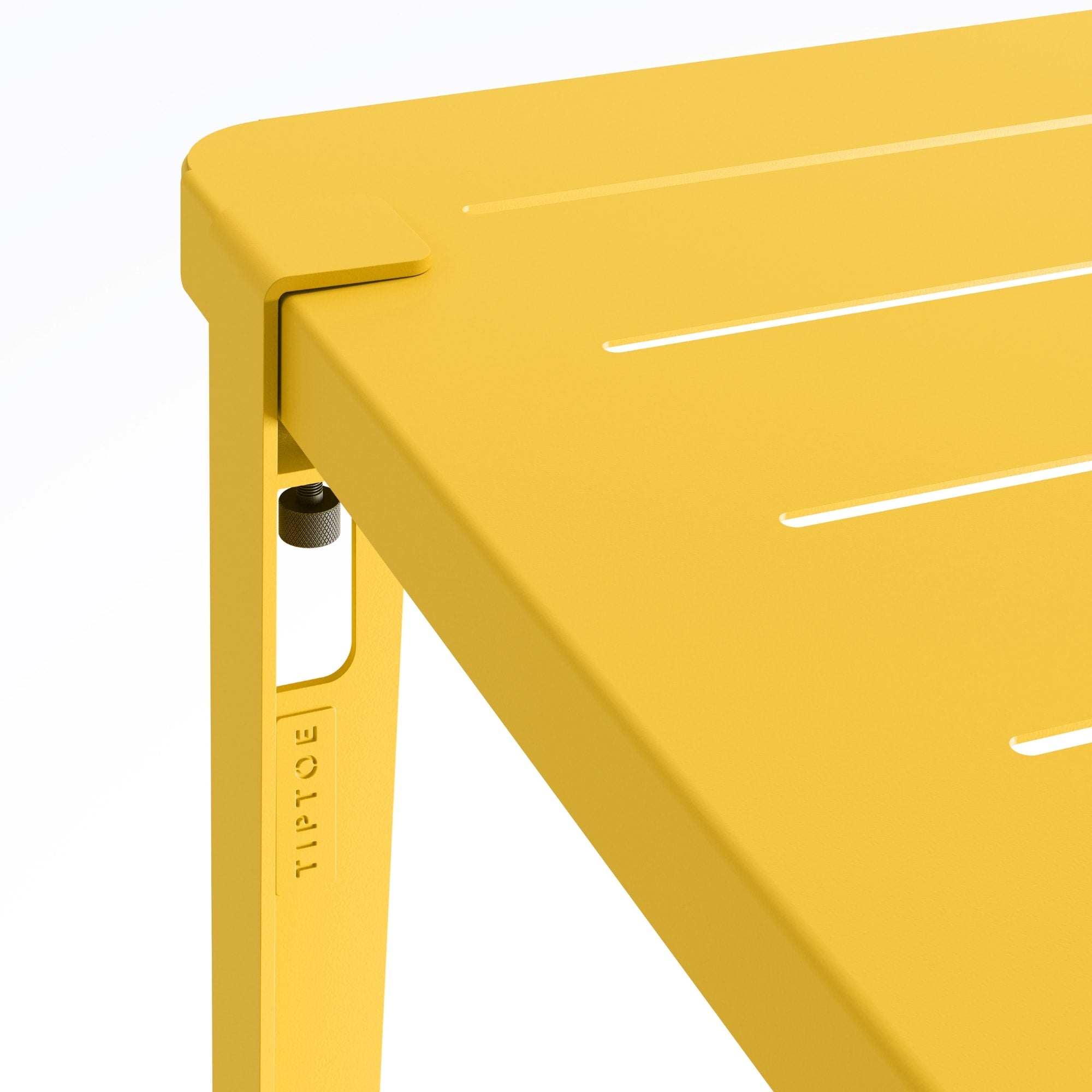 Zoom sur l’angle de la table de jardin Tiptoe en métal jaune soleil, montrant le système de fixation du pied et les rainures du plateau.