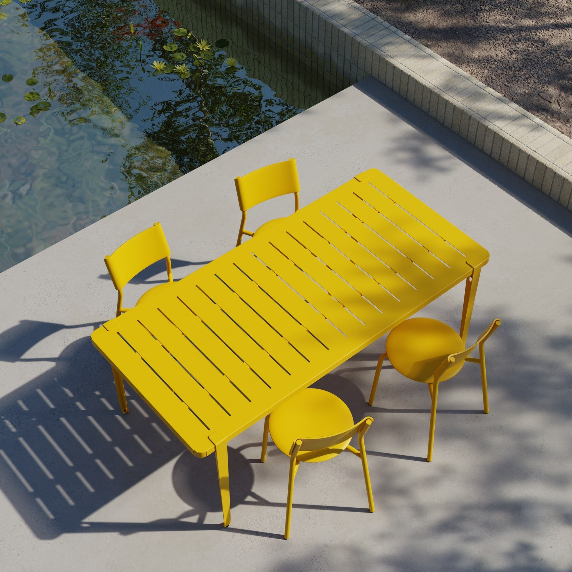 Vue en plongée d’une table de jardin Tiptoe jaune et de quatre chaises assorties, installées en extérieur près d’un bassin.