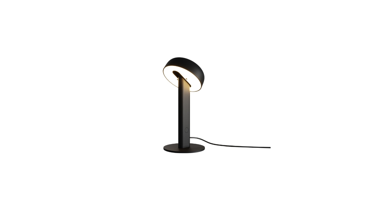 Lampe de table Nod en métal noir, base ronde et tête inclinée, allumée