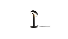 Lampe de table Nod en métal noir, base ronde et tête inclinée, allumée