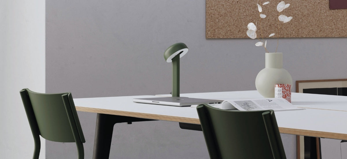 Espace de coworking avec une lampe Nod  verte, posée sur une table de réunion en bois.