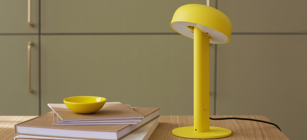 Gros plan sur la lampe de table Nod en jaune, mise en valeur sur un bureau en bois