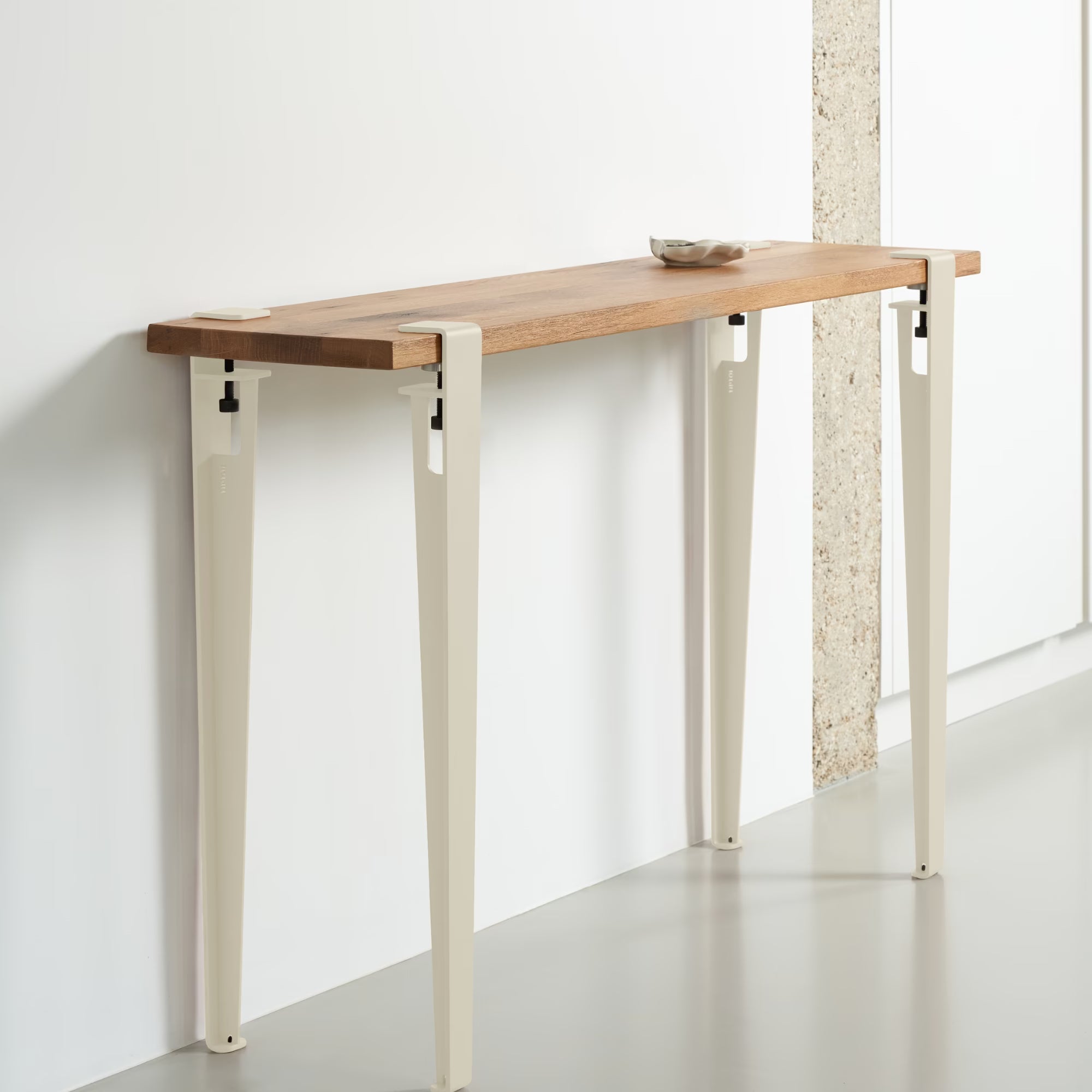 Console en bois massif et métal blanc crème, installée contre un mur clair, ambiance moderne et épurée.