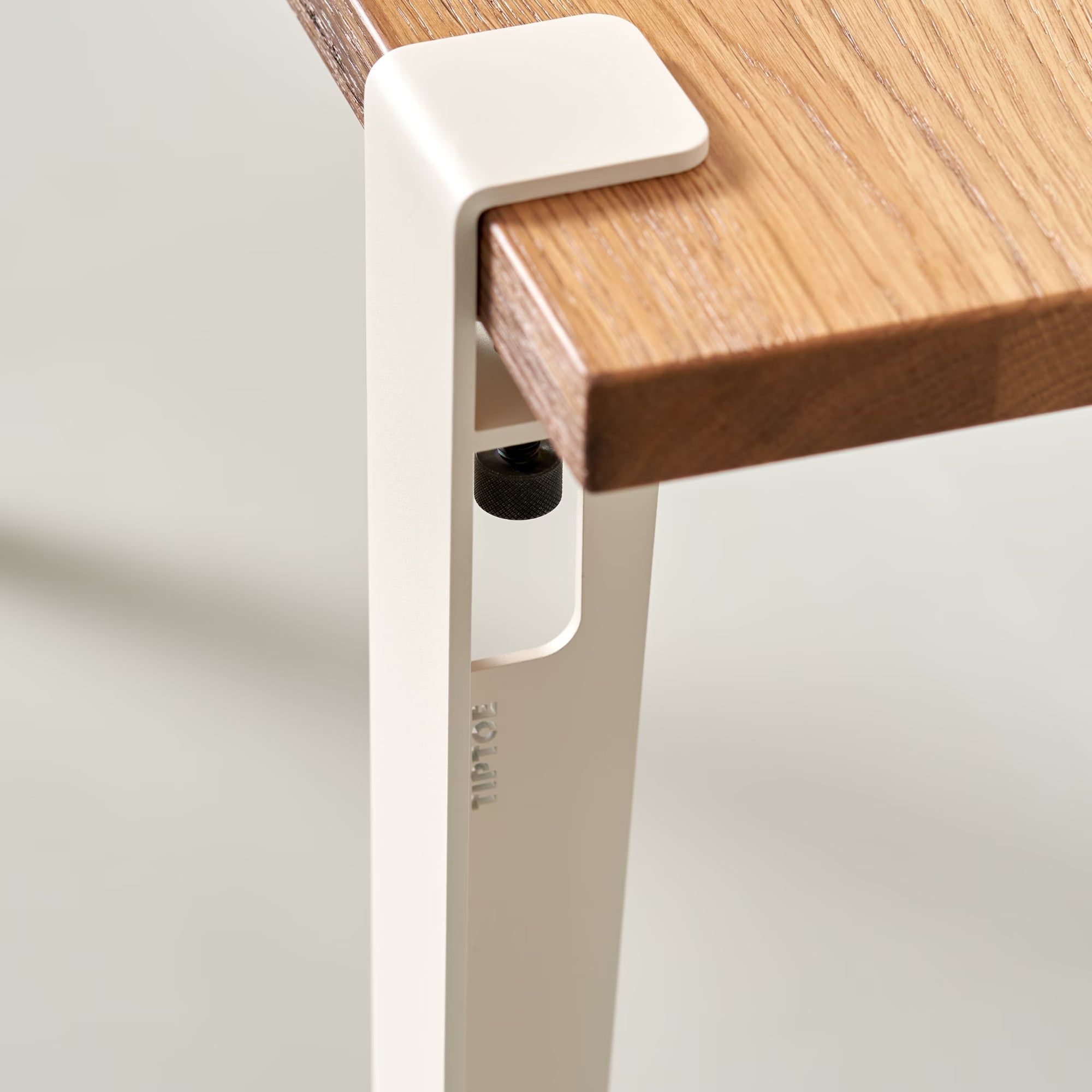 Détail de la console en bois massif et métal blanc crème, zoom sur le piètement en acier thermolaqué fixé au plateau.