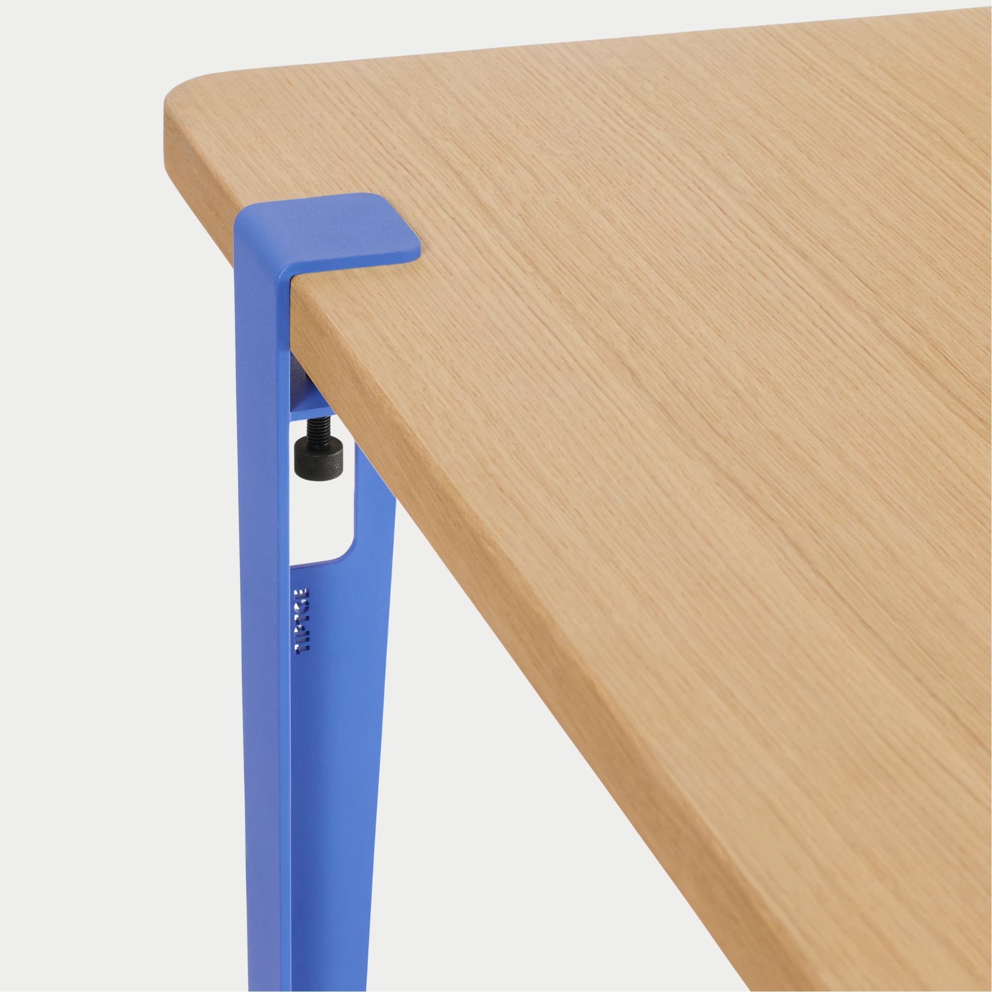 Vue rapprochée : plateau bois clair et fixation métal bleu azur, détail de l’assemblage sur fond blanc.