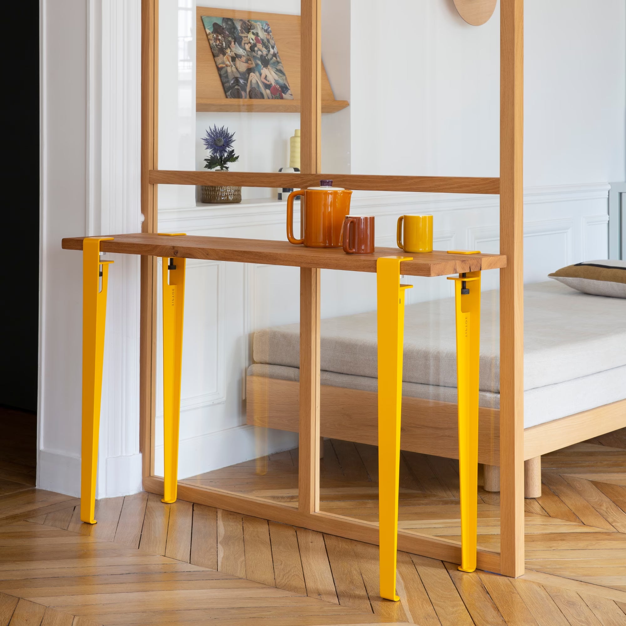 Console en bois massif avec pieds en métal jaune brioche, installée dans une chambre lumineuse au sol parquet