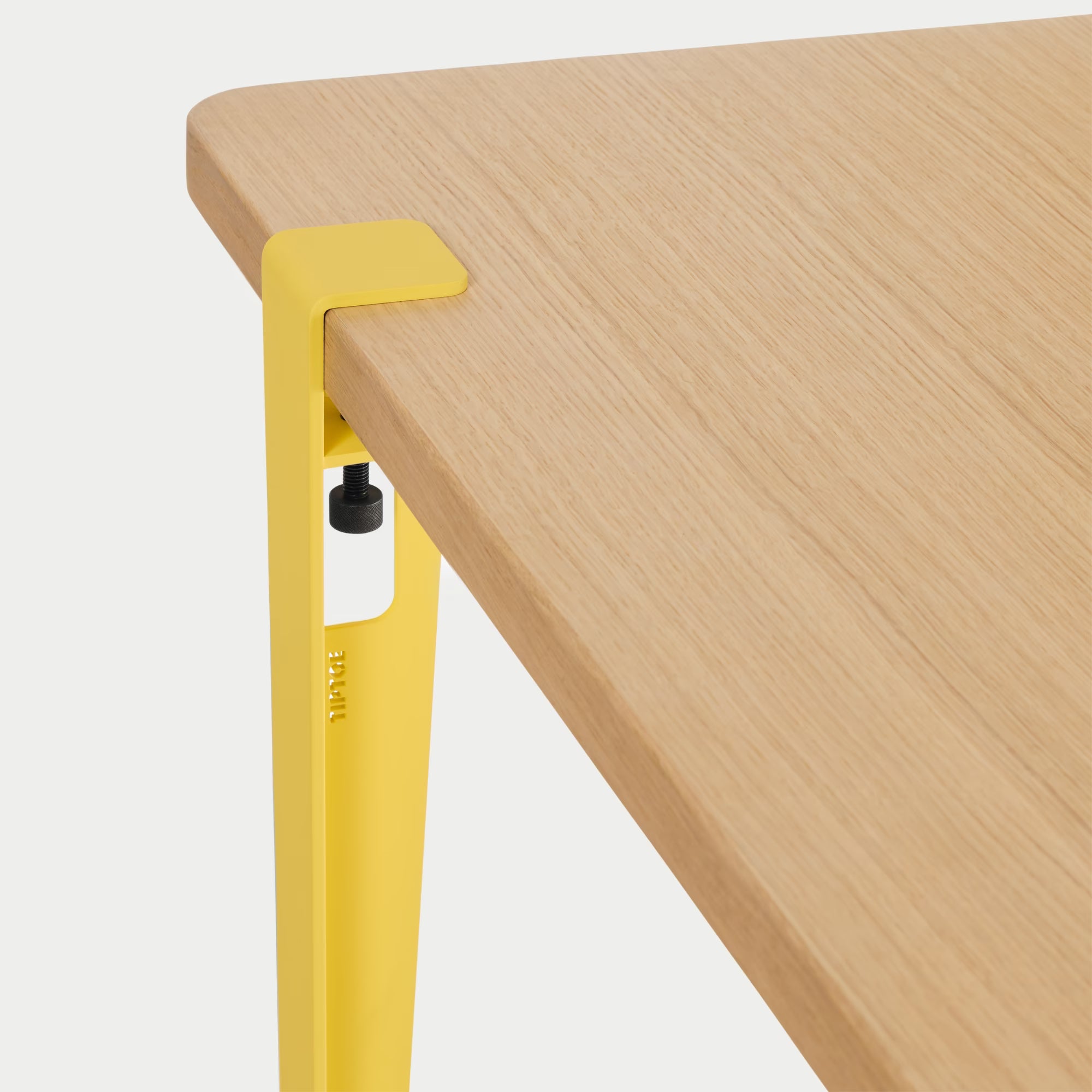 Vue rapprochée : plateau bois clair et fixation métal jaune brioche, détail de l’assemblage sur fond blanc.