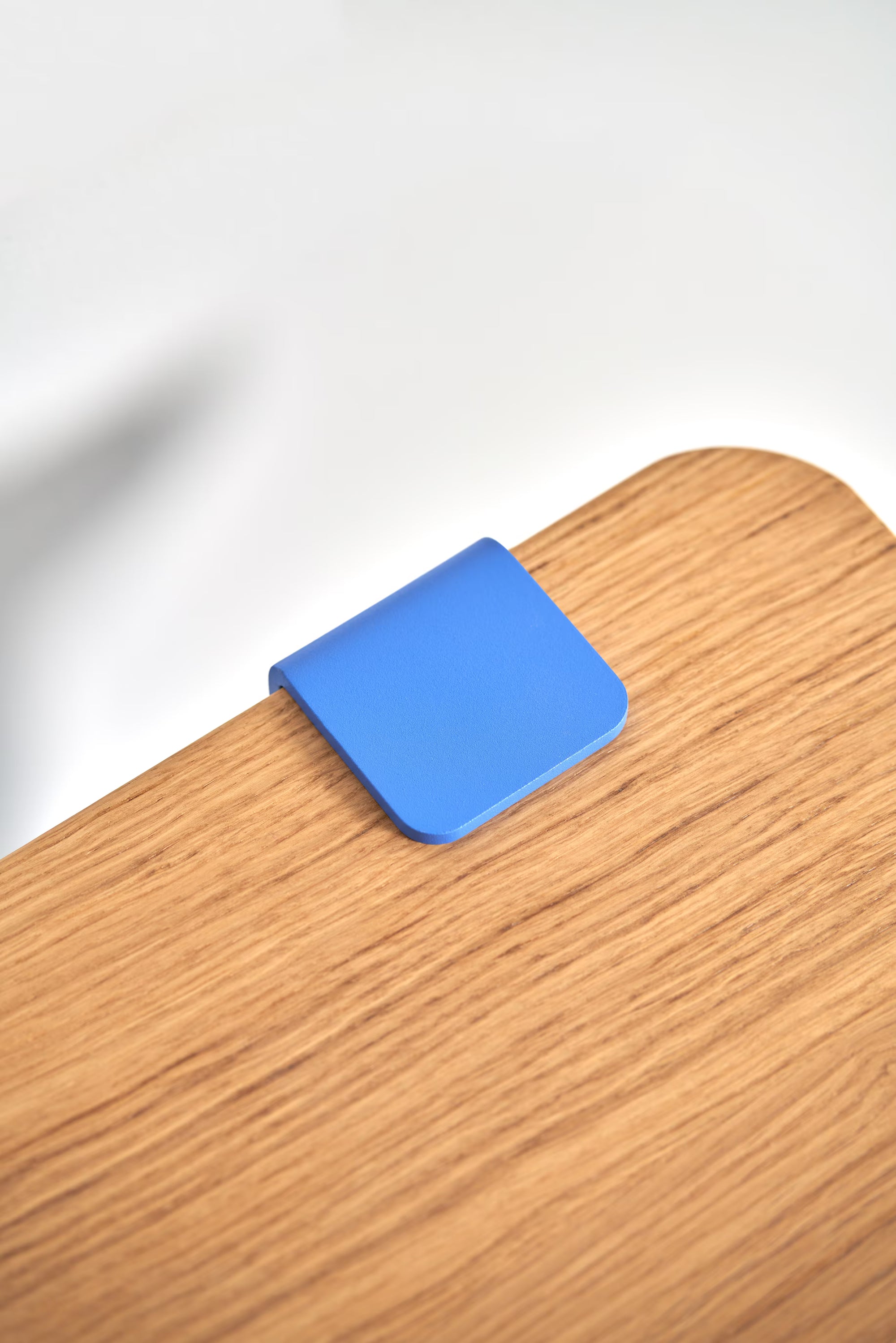Gros plan sur le plateau en bois massif avec fixation métallique bleu azur, texture et détail visibles.