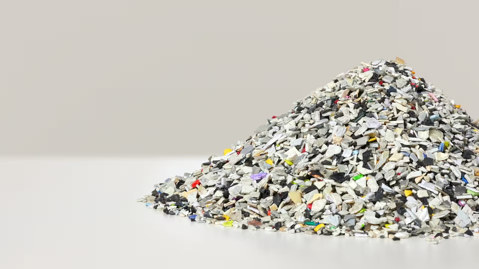 Granulés de plastique recyclé multicolores utilisés pour la fabrication de mobilier écoresponsable dans une logique d’économie circulaire.